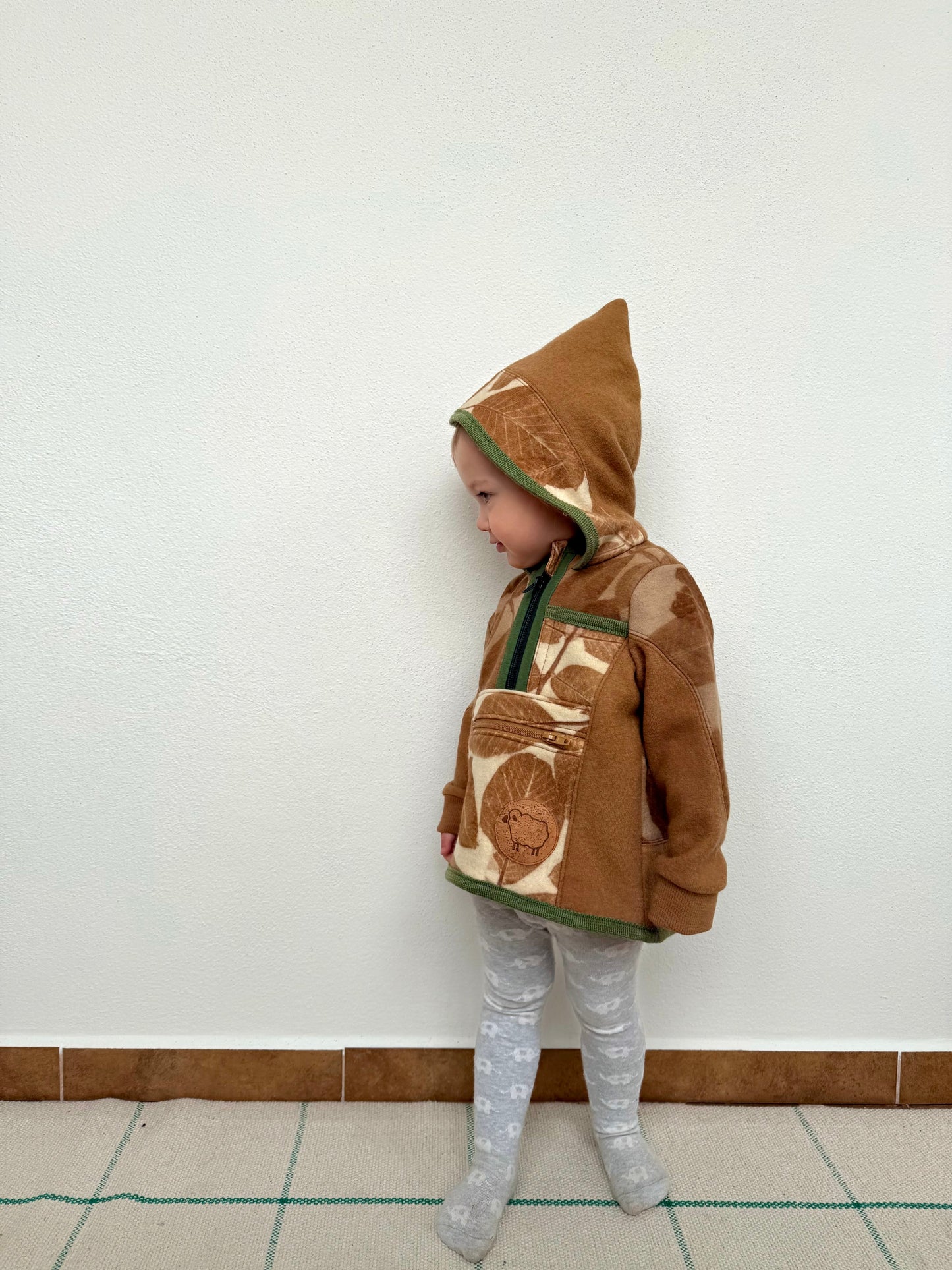 Child wearing a brown hoodie with walnut leaves eco-print by DOT 'N' POT