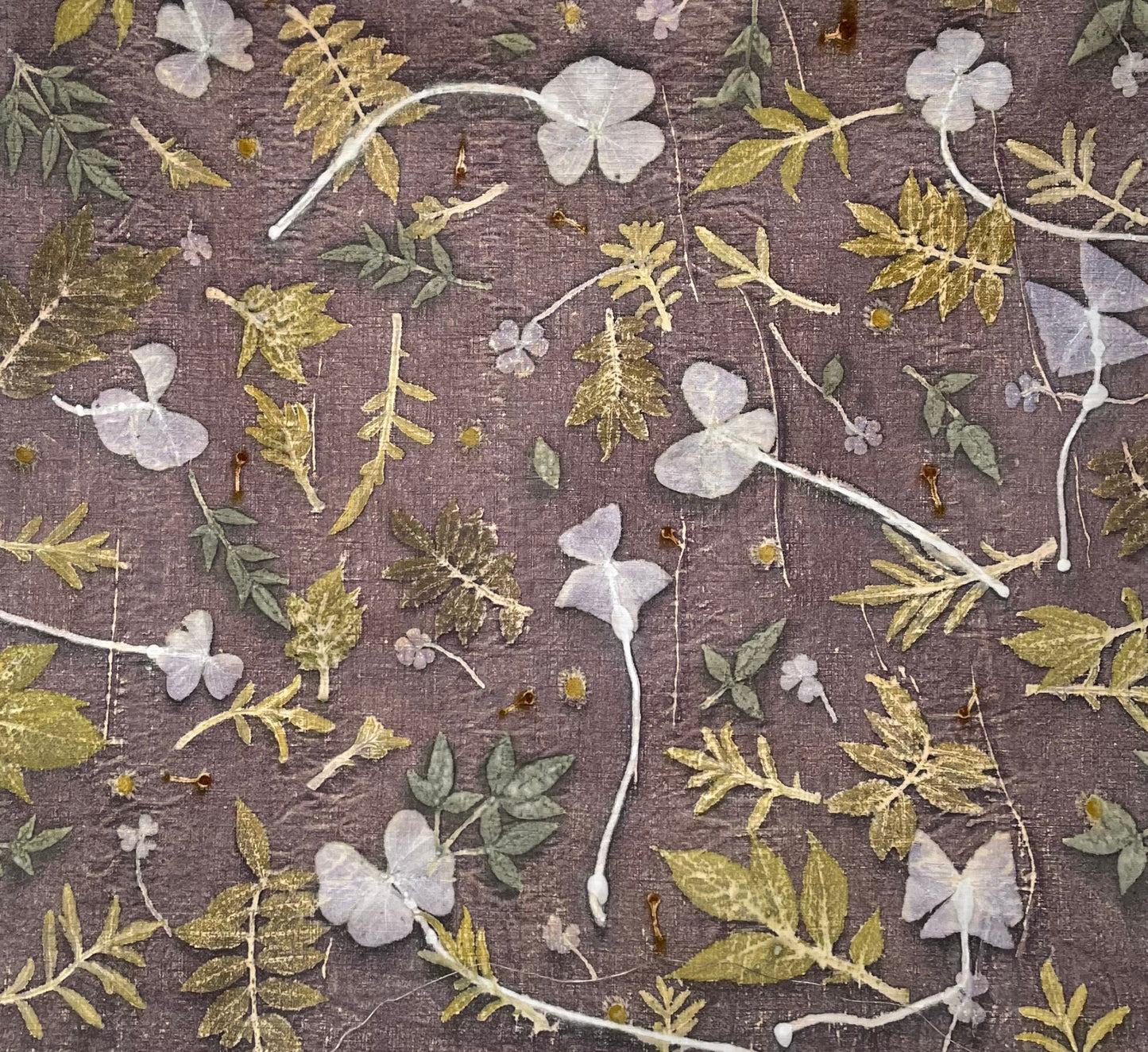 Eco-printed and discharged linen fabric with colorful leaves and puprle background, naturally dyed