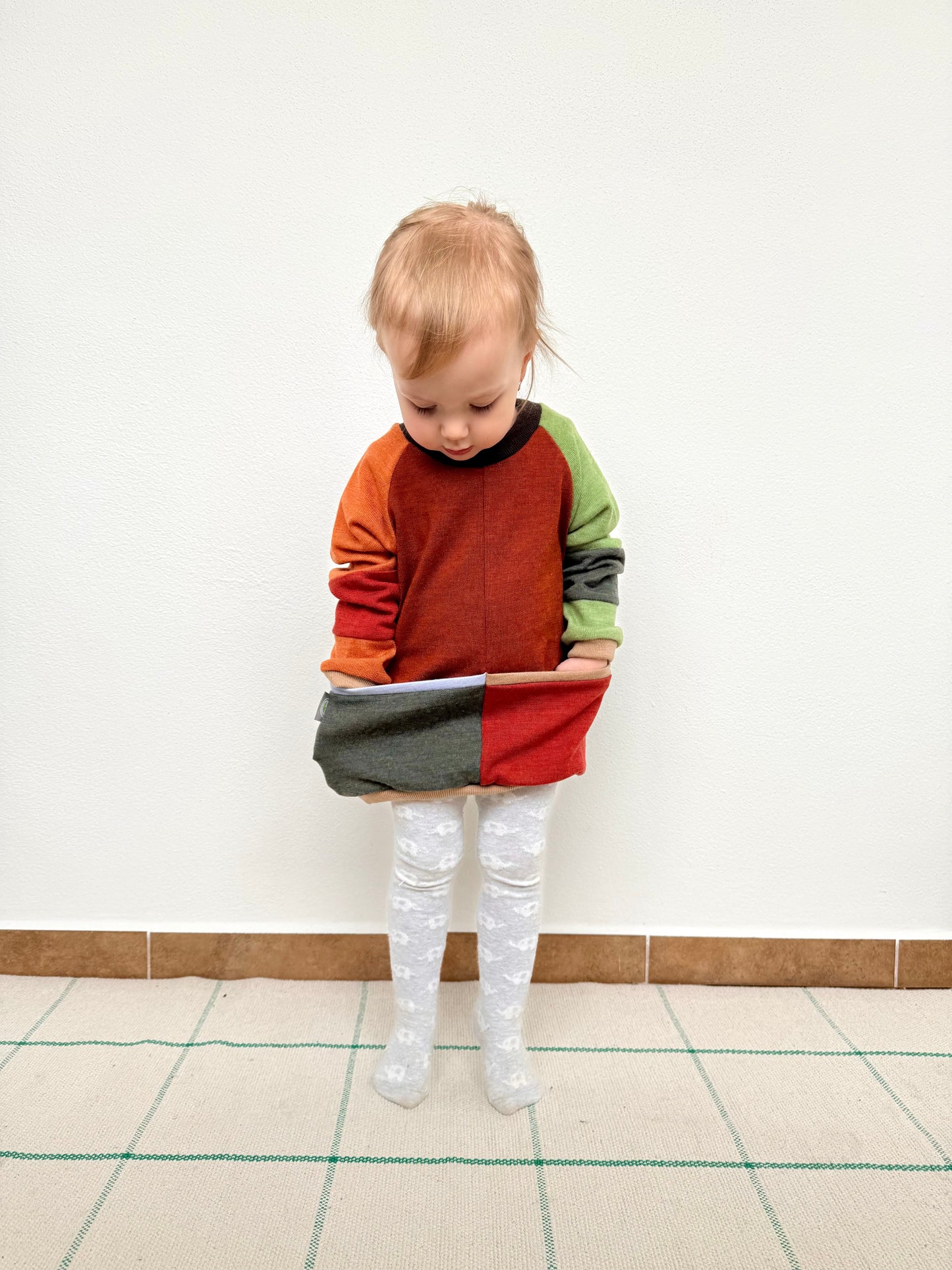 child wearing an upcycled merino wool sweater with red, orange, brown and green color blocks by DOT 'N' POT