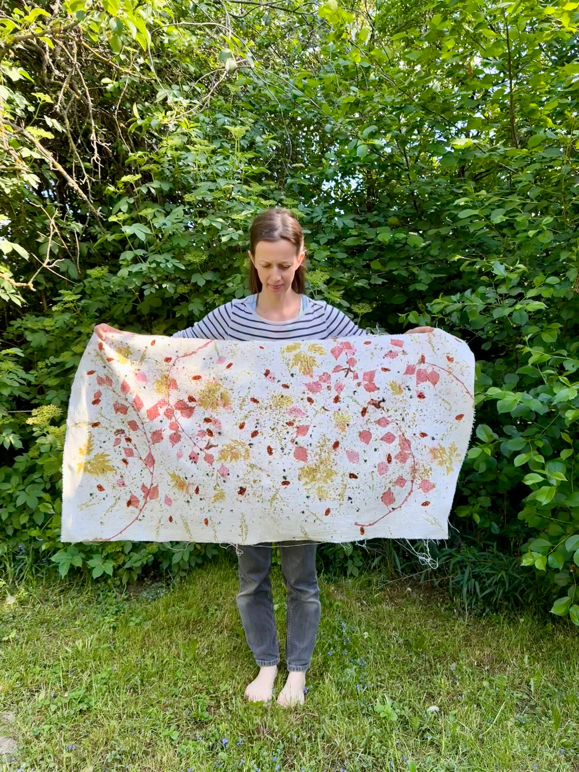 Person holding an eco-printed hemp fabric with a floral pattern in a natural setting
