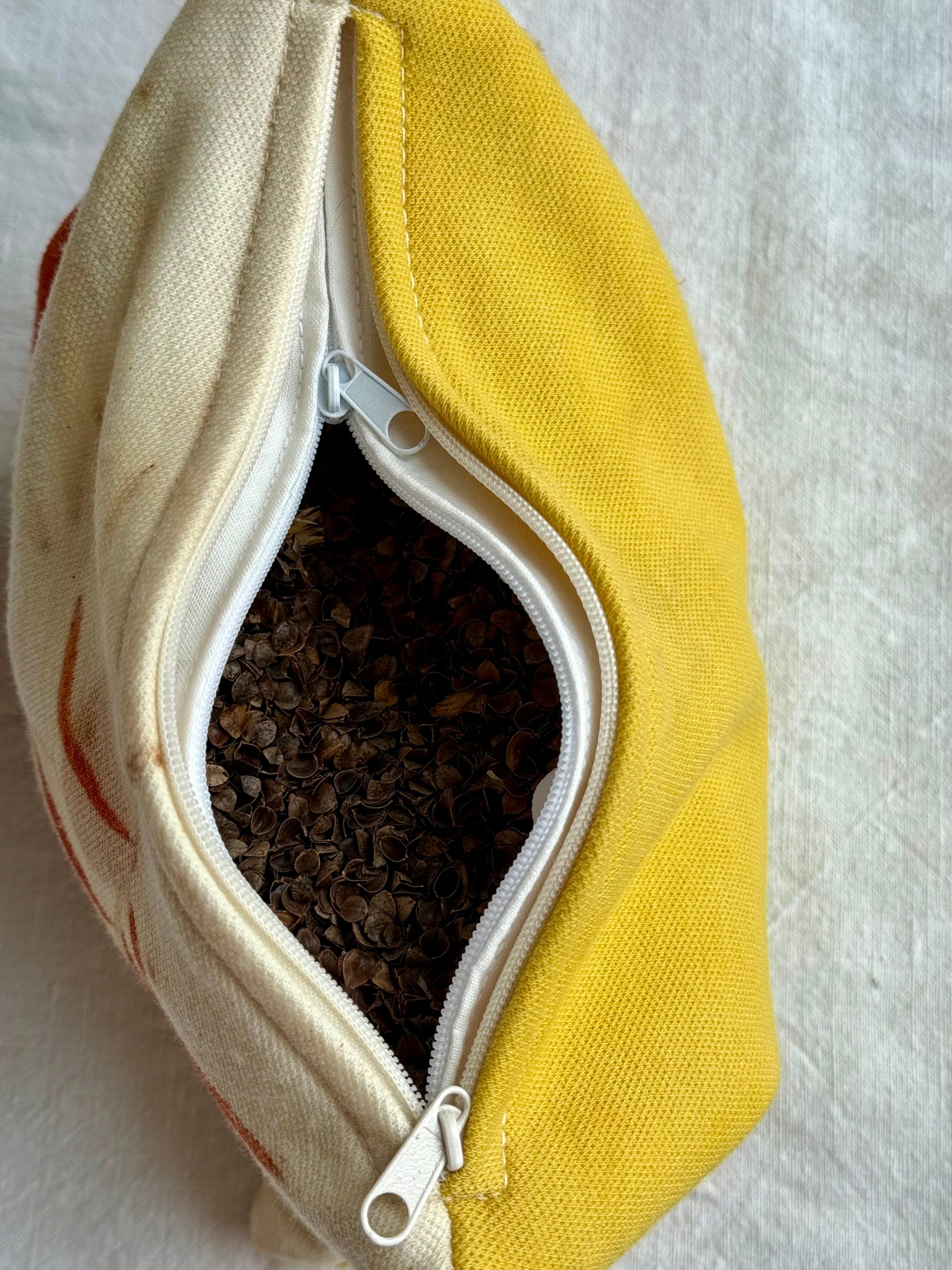 Natural yellow and beige fabric herbal pillow with a zipper, containing buckwheat hulls