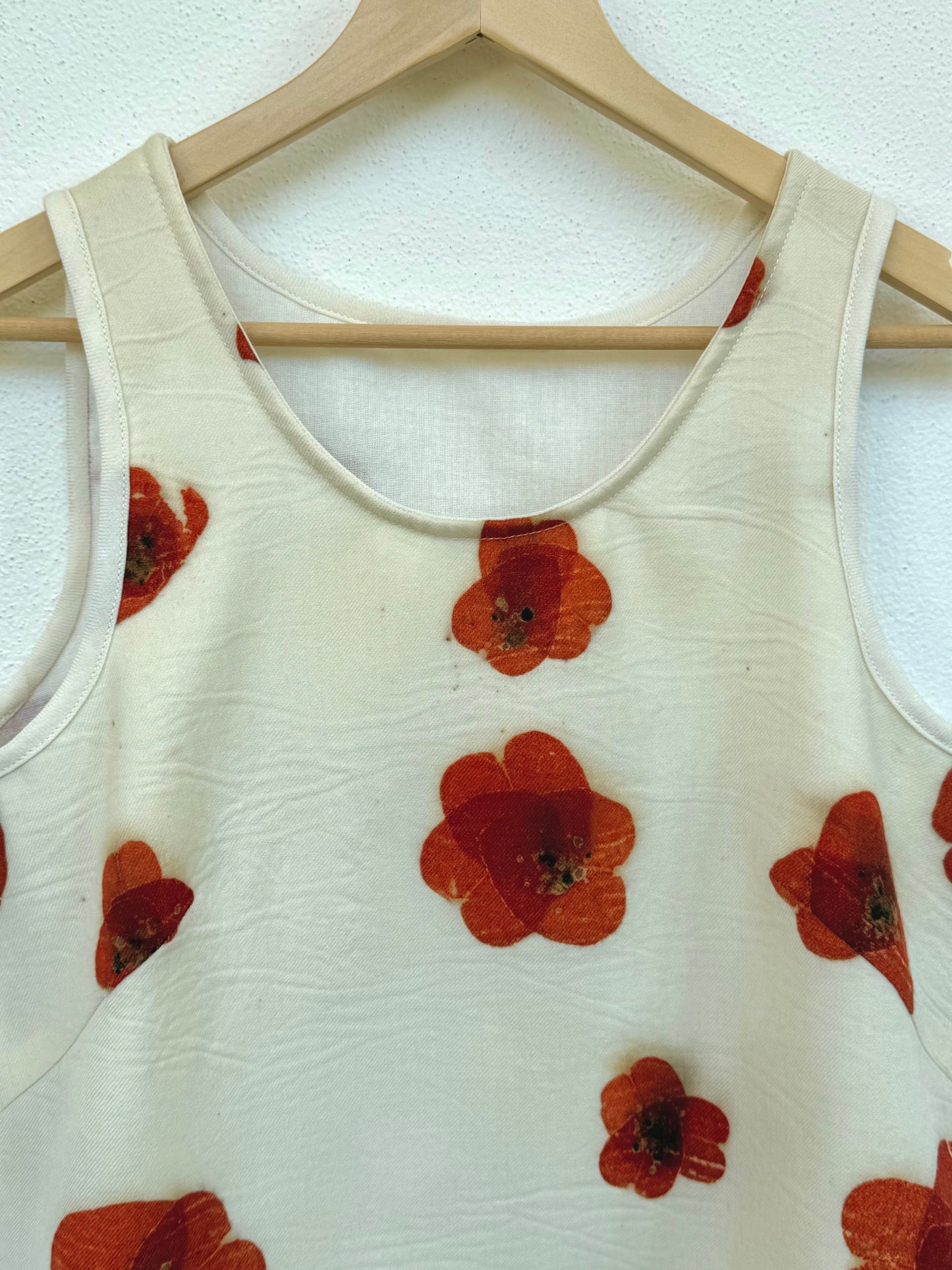 Cream tank top with red floral eco-printed patterns on a wooden hanger against a white background by DOT 'N' POT