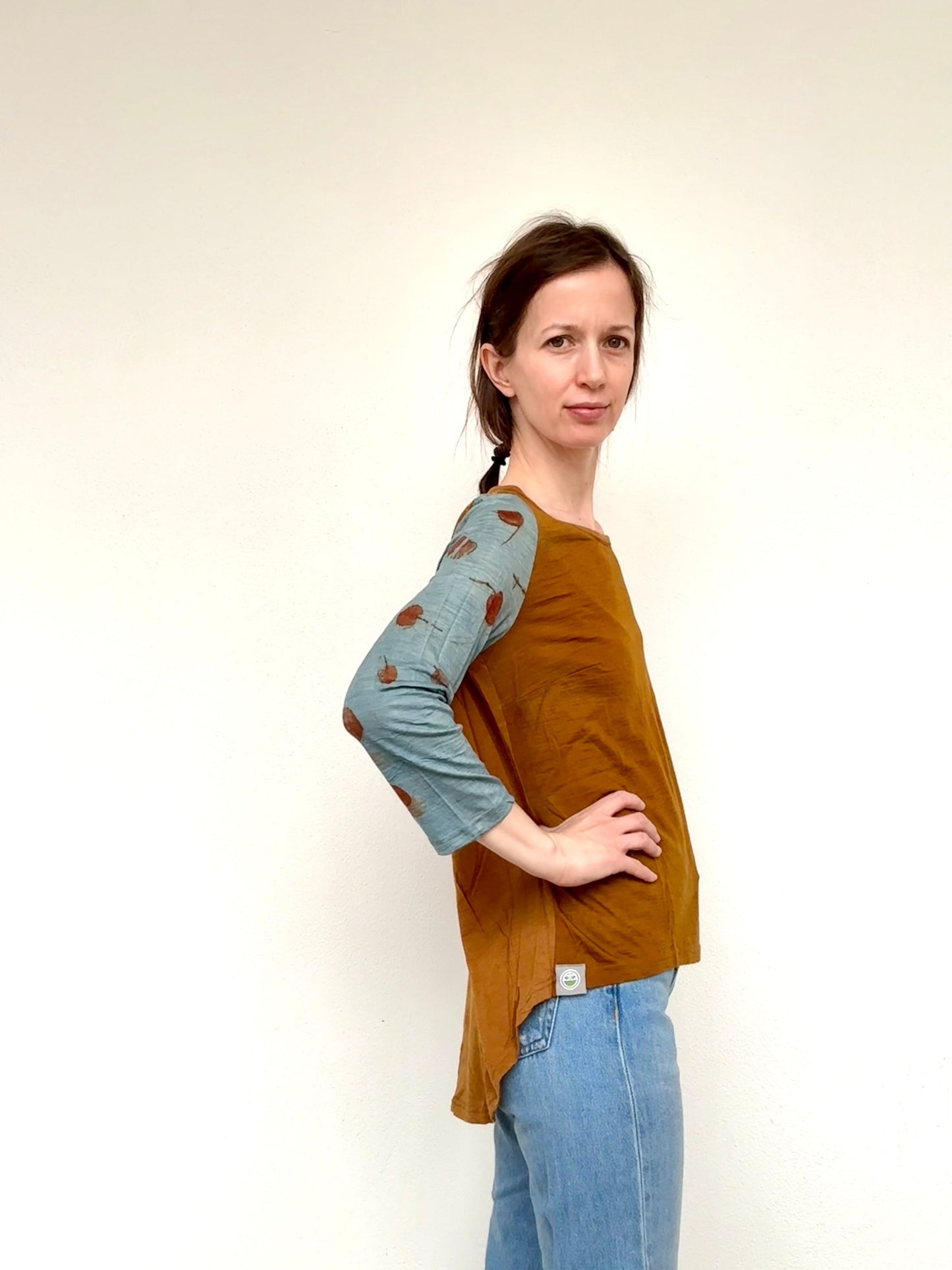 Woman wearing a brown and blue naturally dyed onion skins-indigo-eucalyptus top with a plain background