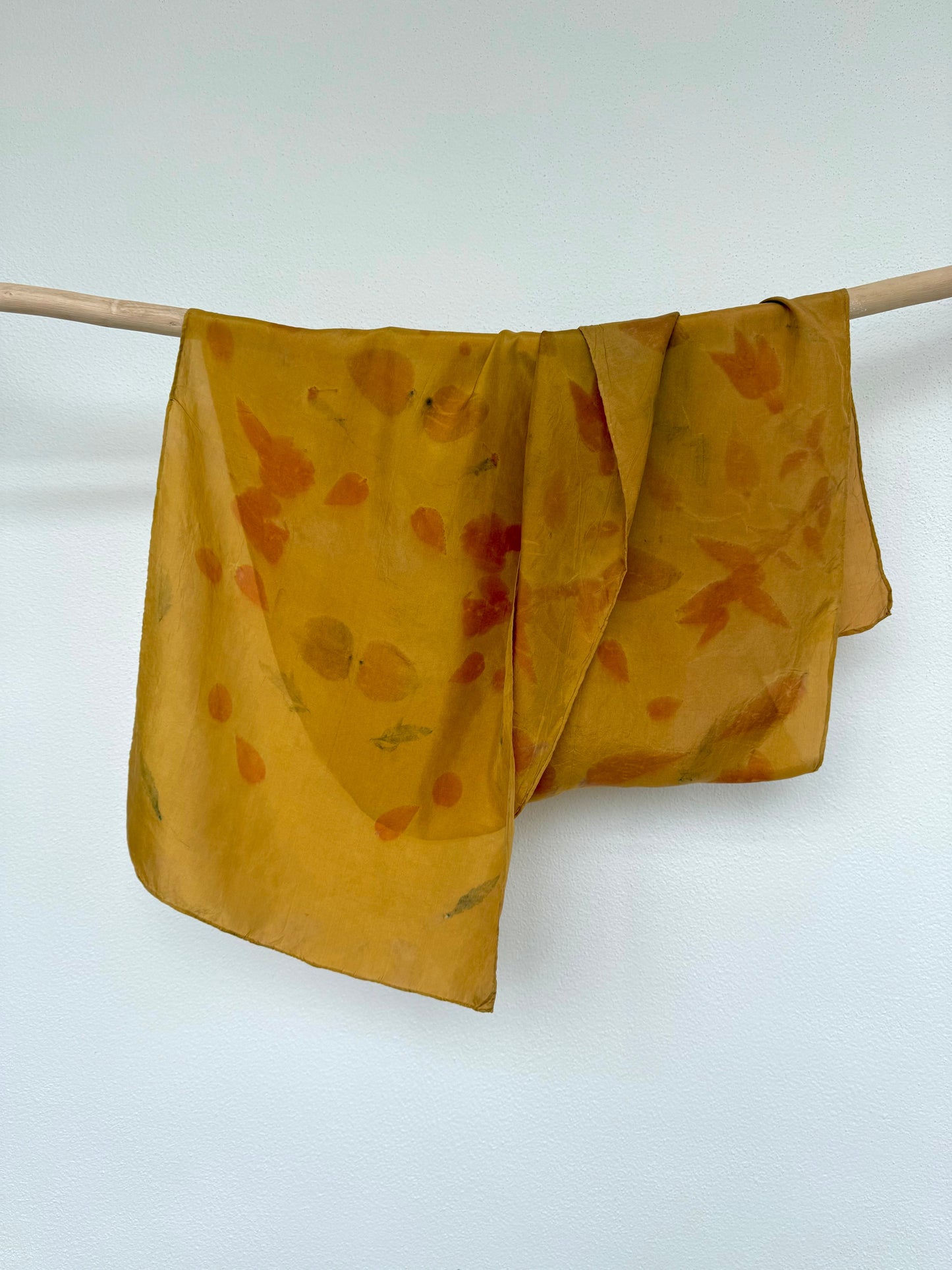 silk scarf naturally dyed with onion skins and eco-printed with eucalyptus leaves by DOT 'N' POT hanging from a rod