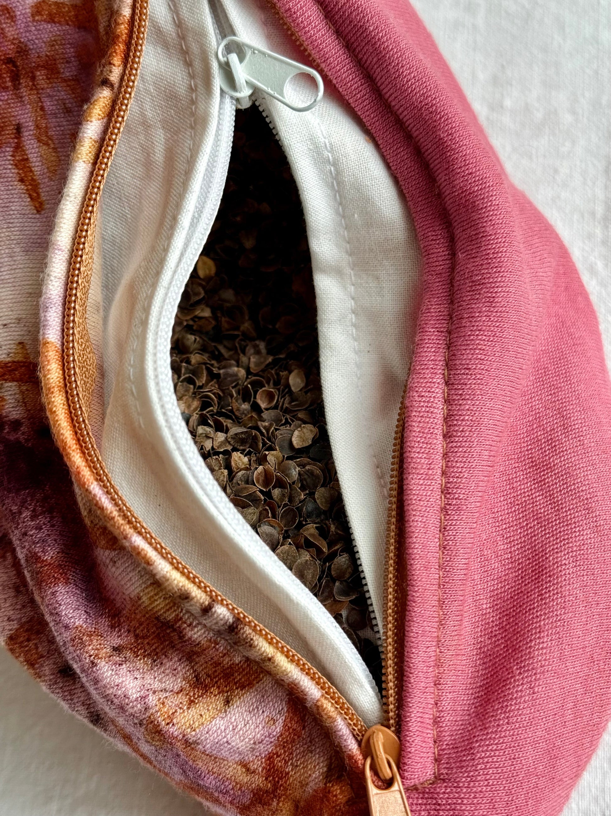 Close-up of a pink purple herbal pillow with a zipper, containing dried herbs and buckwheat hulls