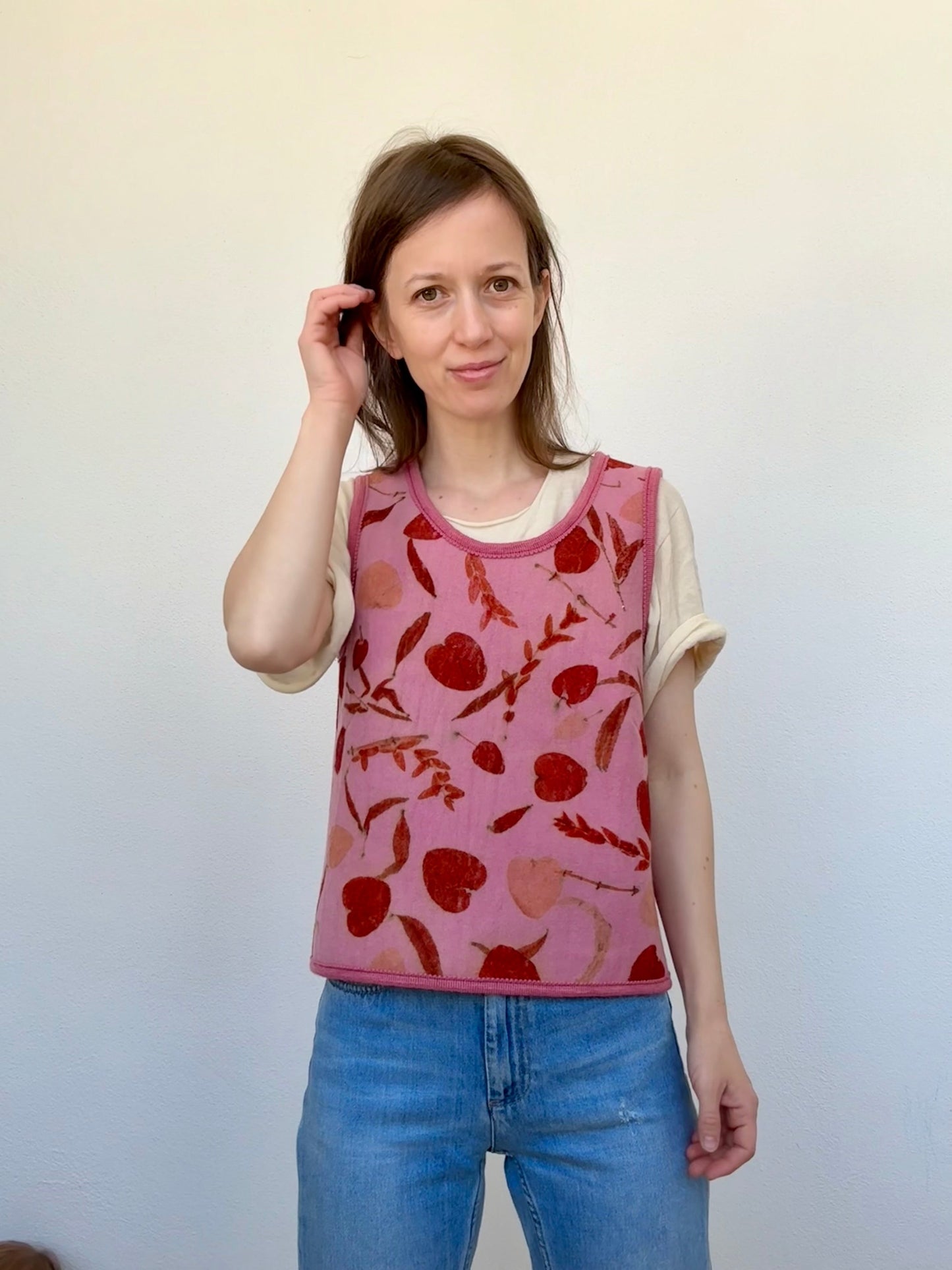 woman wearing a naturally dyed pink vest with eco-printed orange colored eucalyptus leaves 