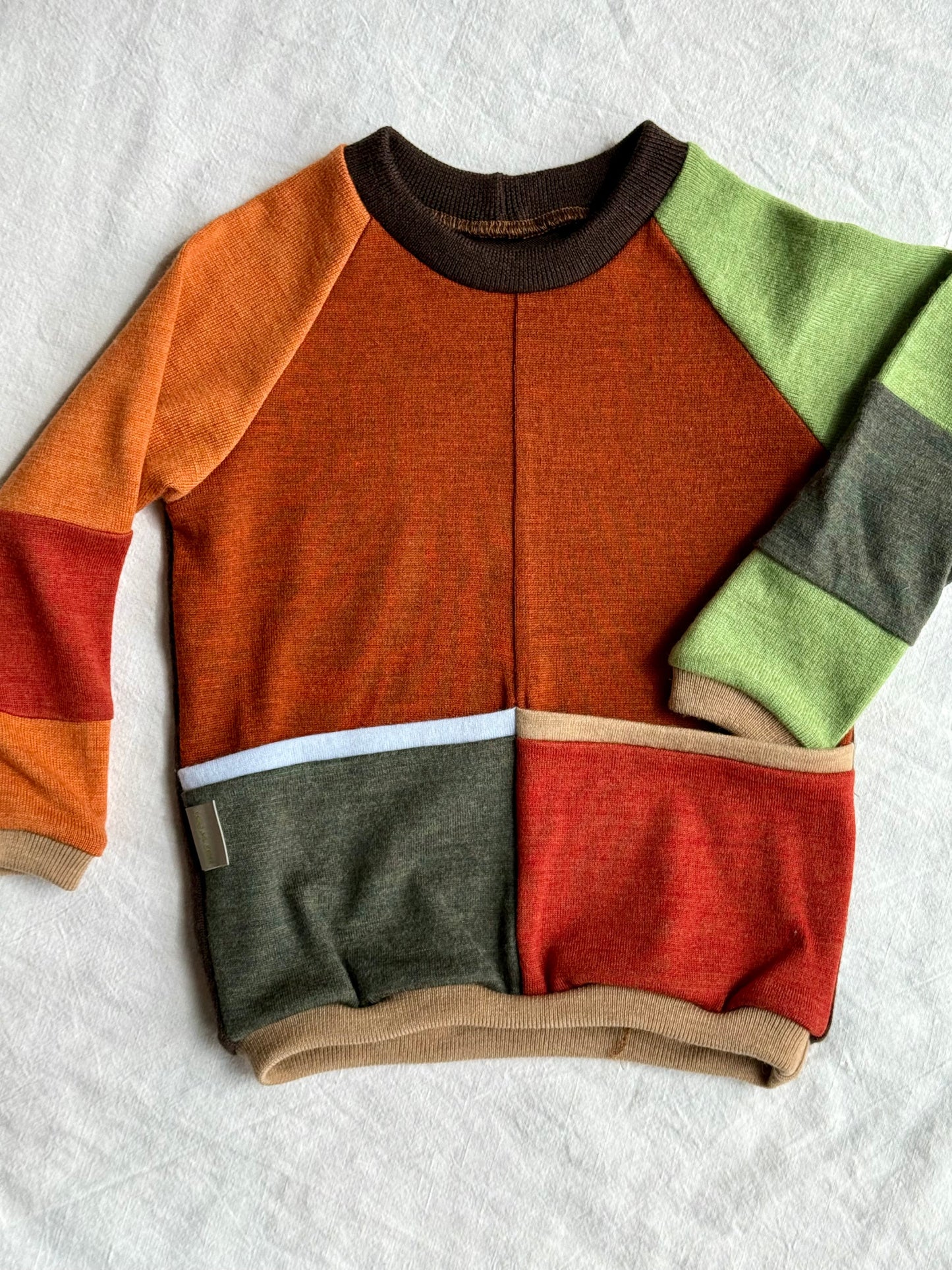 Upcycled color-blocked sweater with brown, green, and red sections from merino wool by DOT 'N' POT