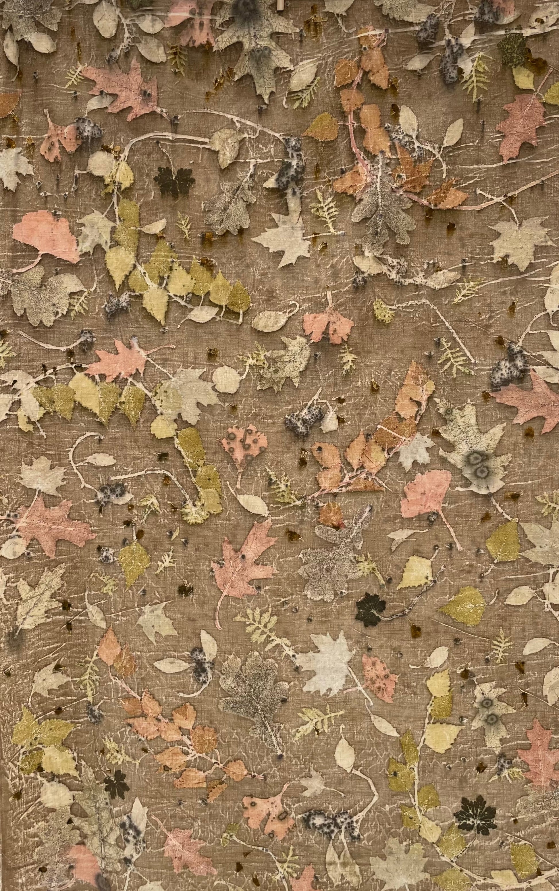 Colorful textile with leaf pattern eco-printed  on a linen fabric with a light brown background 