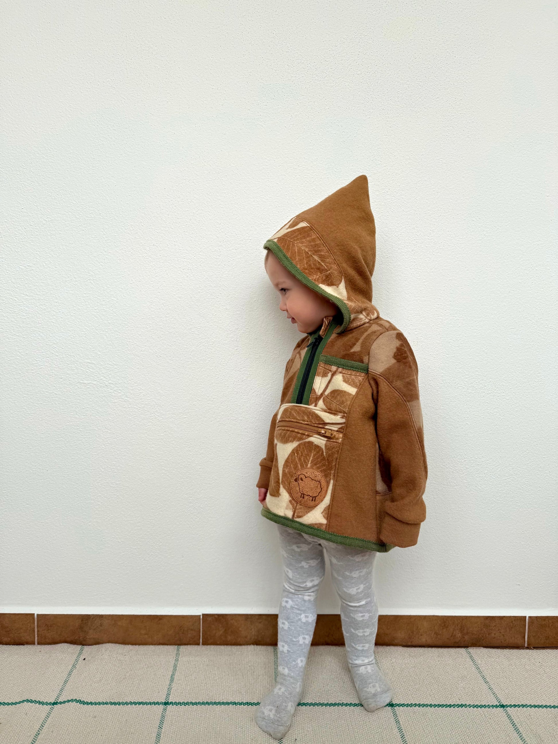 Child wearing a brown hoodie with walnut leaves eco-print by DOT 'N' POT
