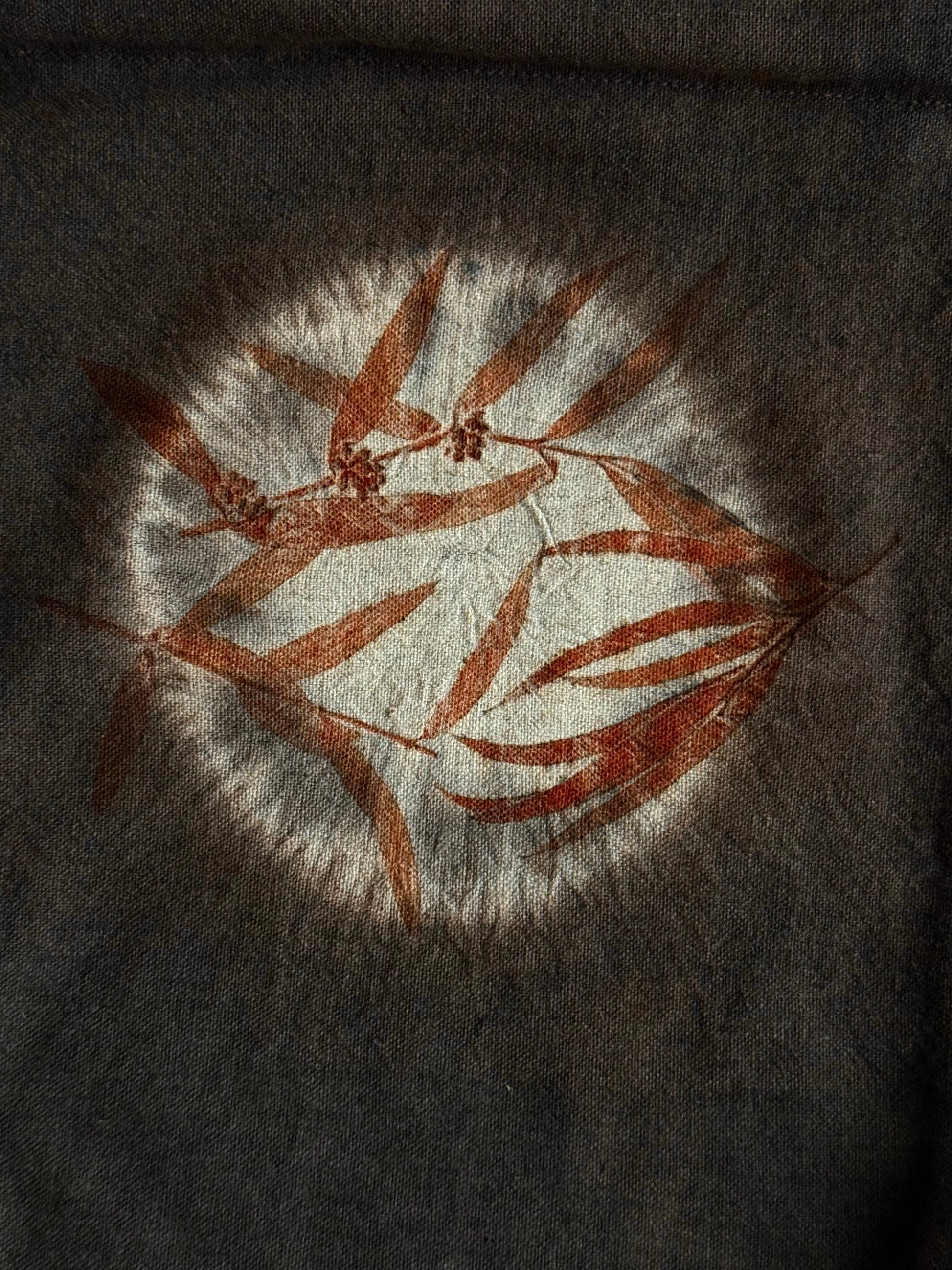 shibori technique close-up with eco-printed eucalyptus leaves and naturally dyed dark brown background