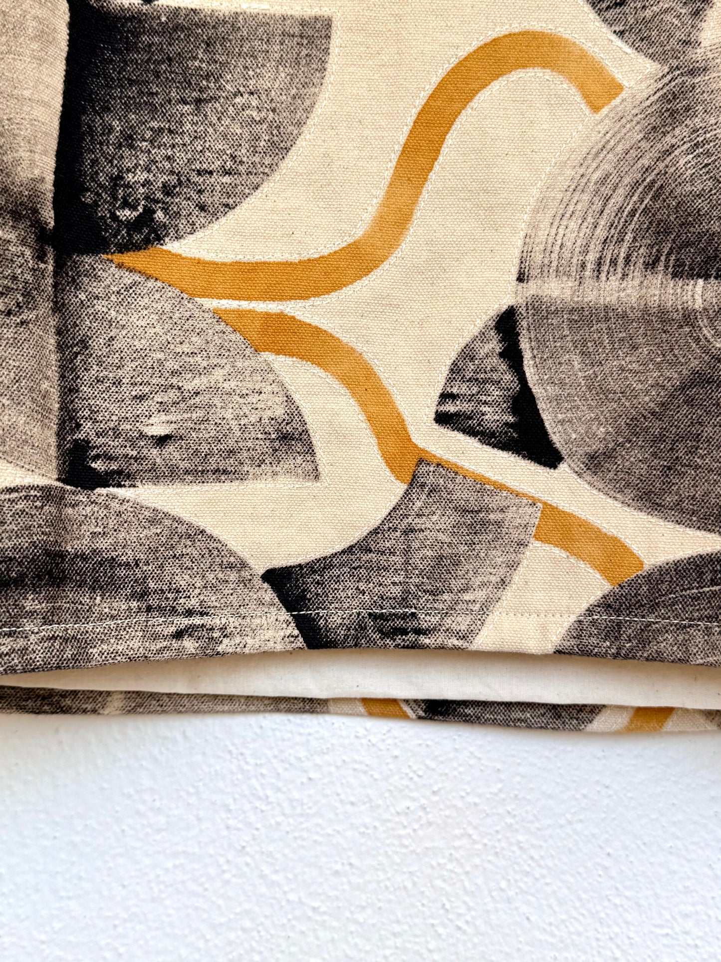 Close-up of a textured fabric with hand-painted abstract pattern on a white background