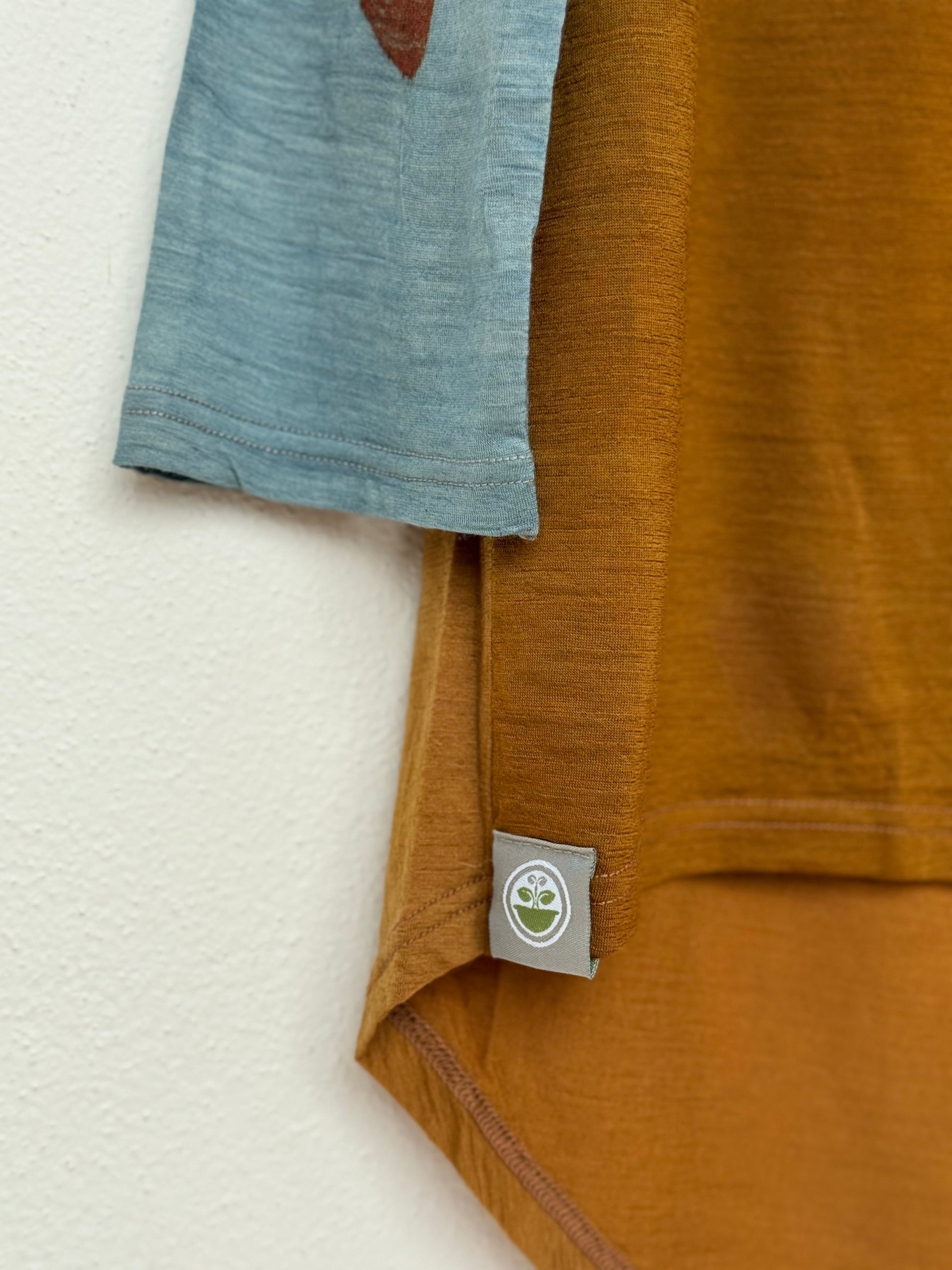 Close-up of a red onion skins dyed shirt with a brand logo tag on a light background by DOT 'N' POT