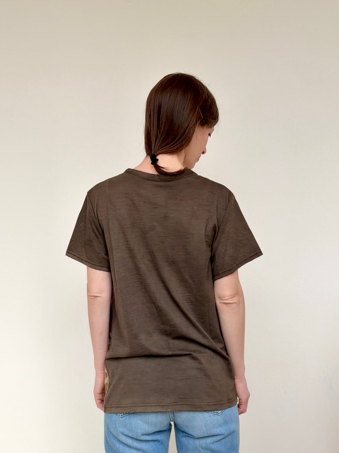 women wearing a naturally dyed merino t-shirt and blue jeans against a plain background