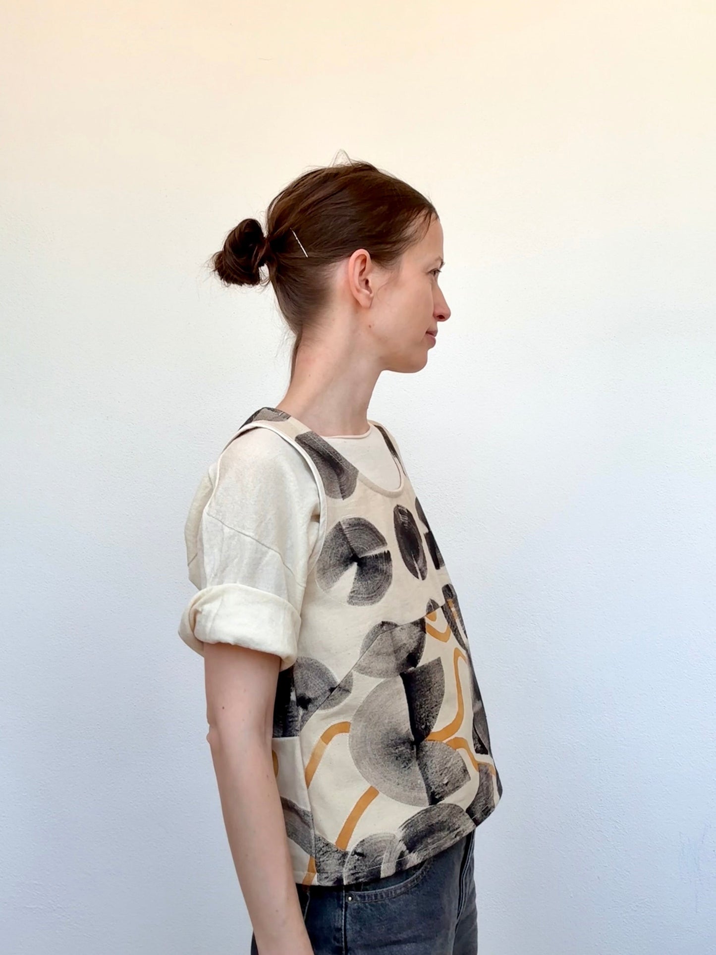 Woman wearing a patterned, naturally hand-painted vest - made with cosmos flowers - view from the side