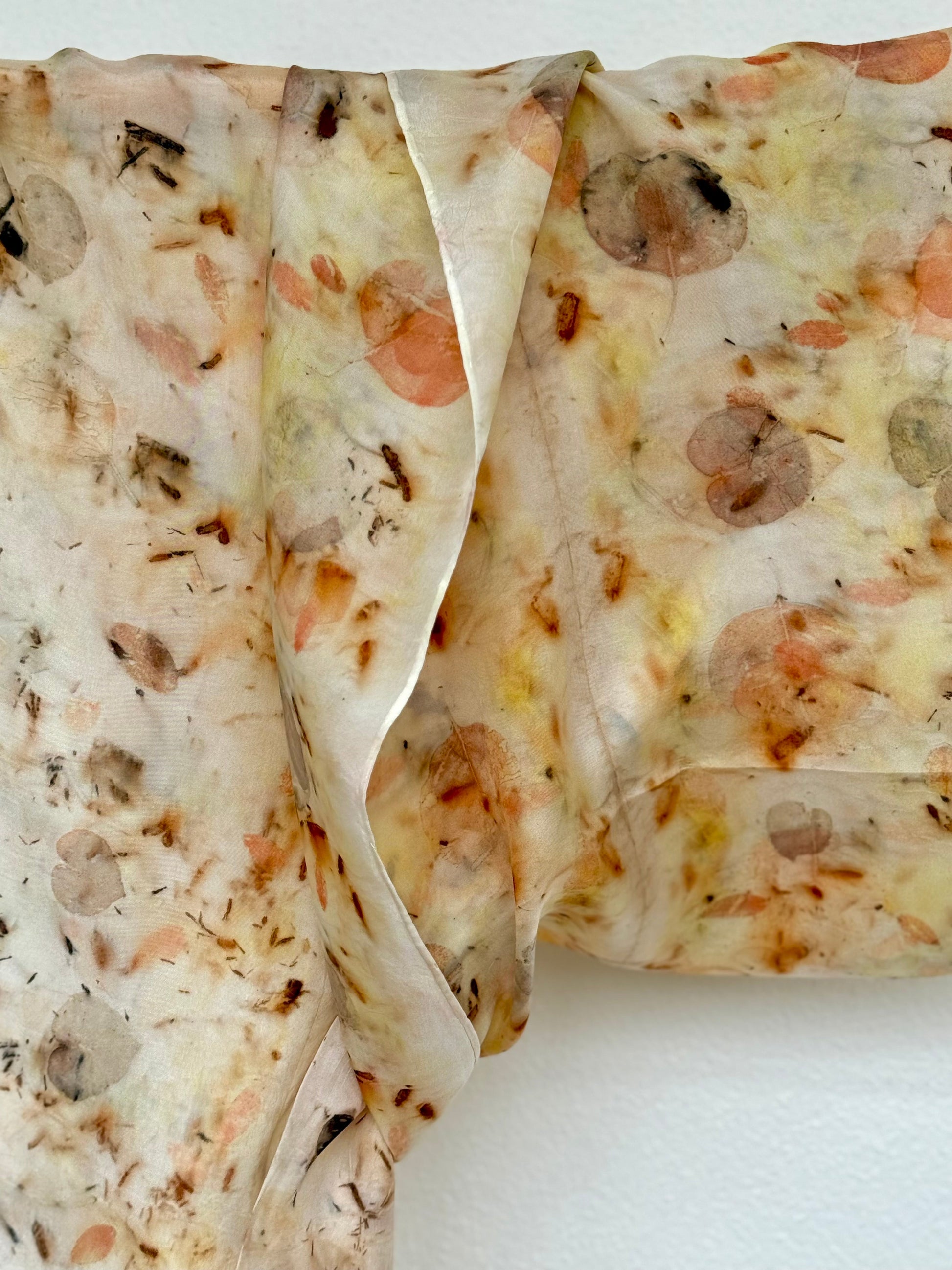 detail of a silk scarf with natural eco-print made with eucalyptus, logwood and safflover