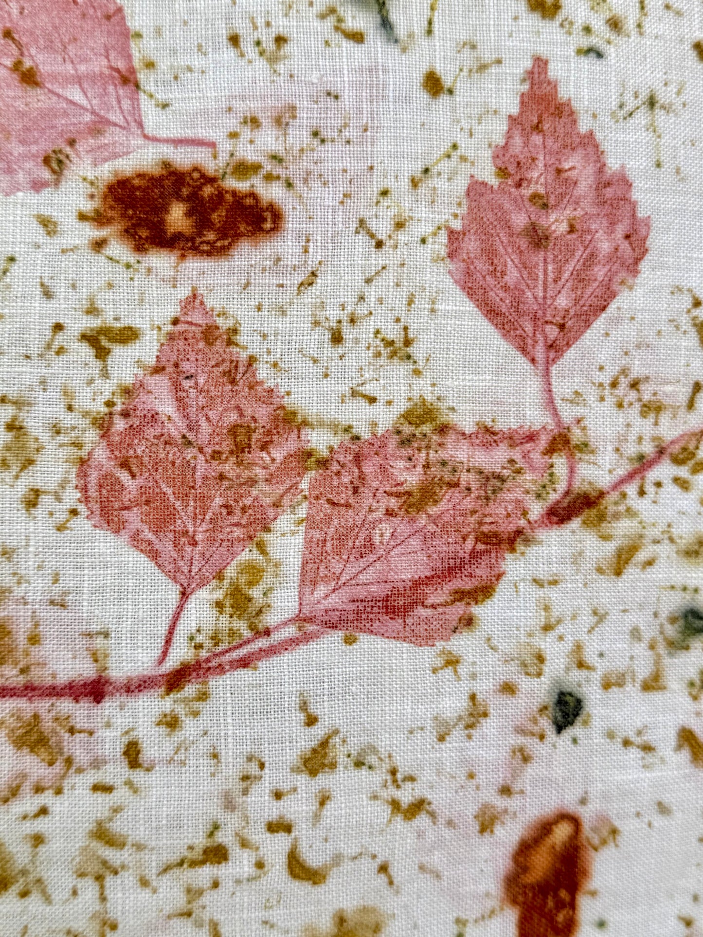Close-up of an eco-printed hemp fabric with pink leaf pattern of madder infused birch leaves and textured background