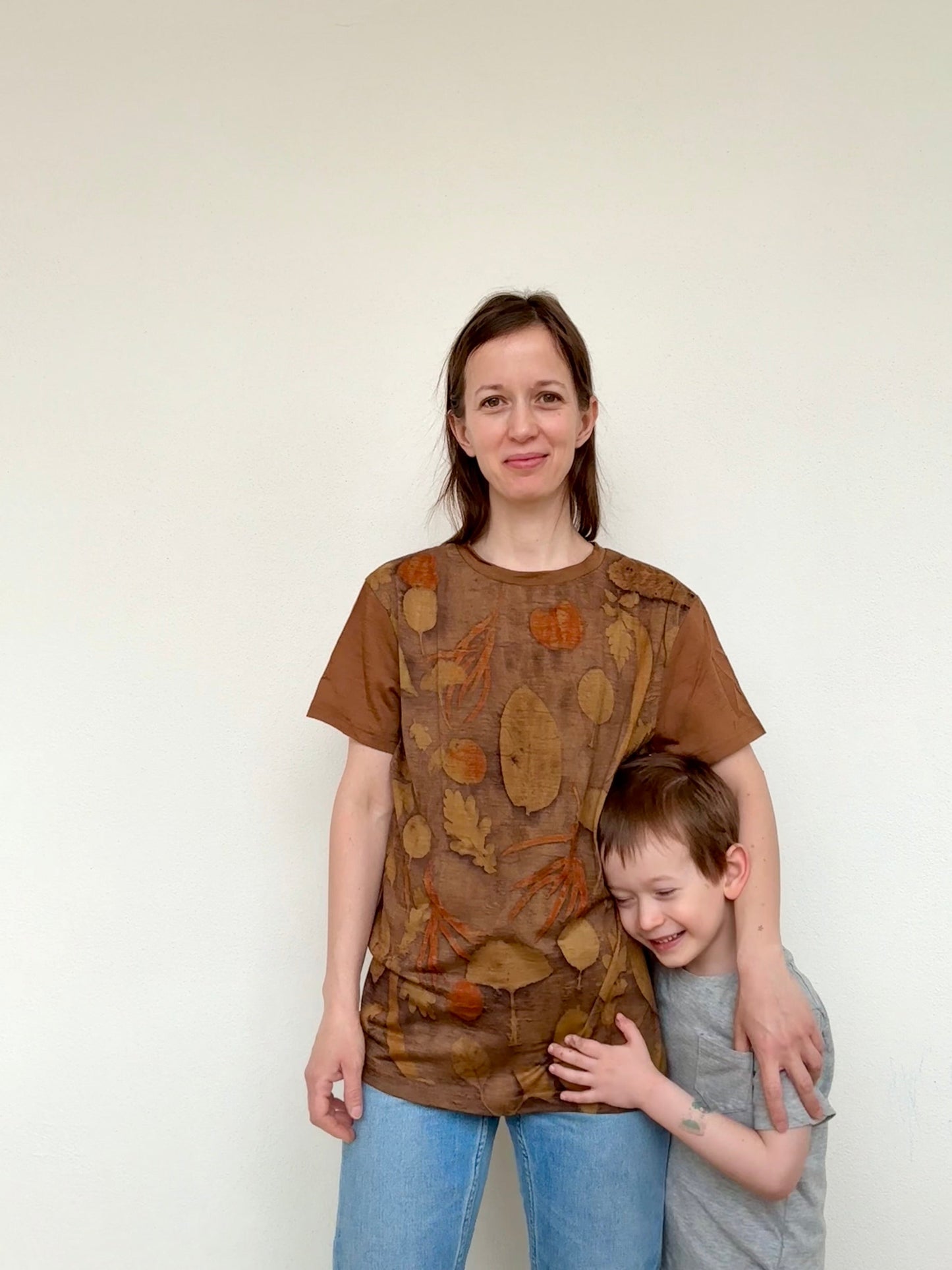 Woman and child wearing brown naturally dyed and eco-printed t-shirt with leaf pattern against a white background by DOT 'N' POT