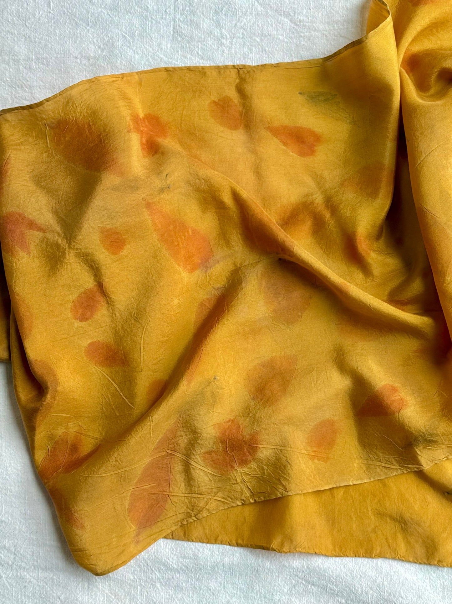 silk scarf naturally dyed with onion skins and eco-printed with eucalyptus leaves on white background