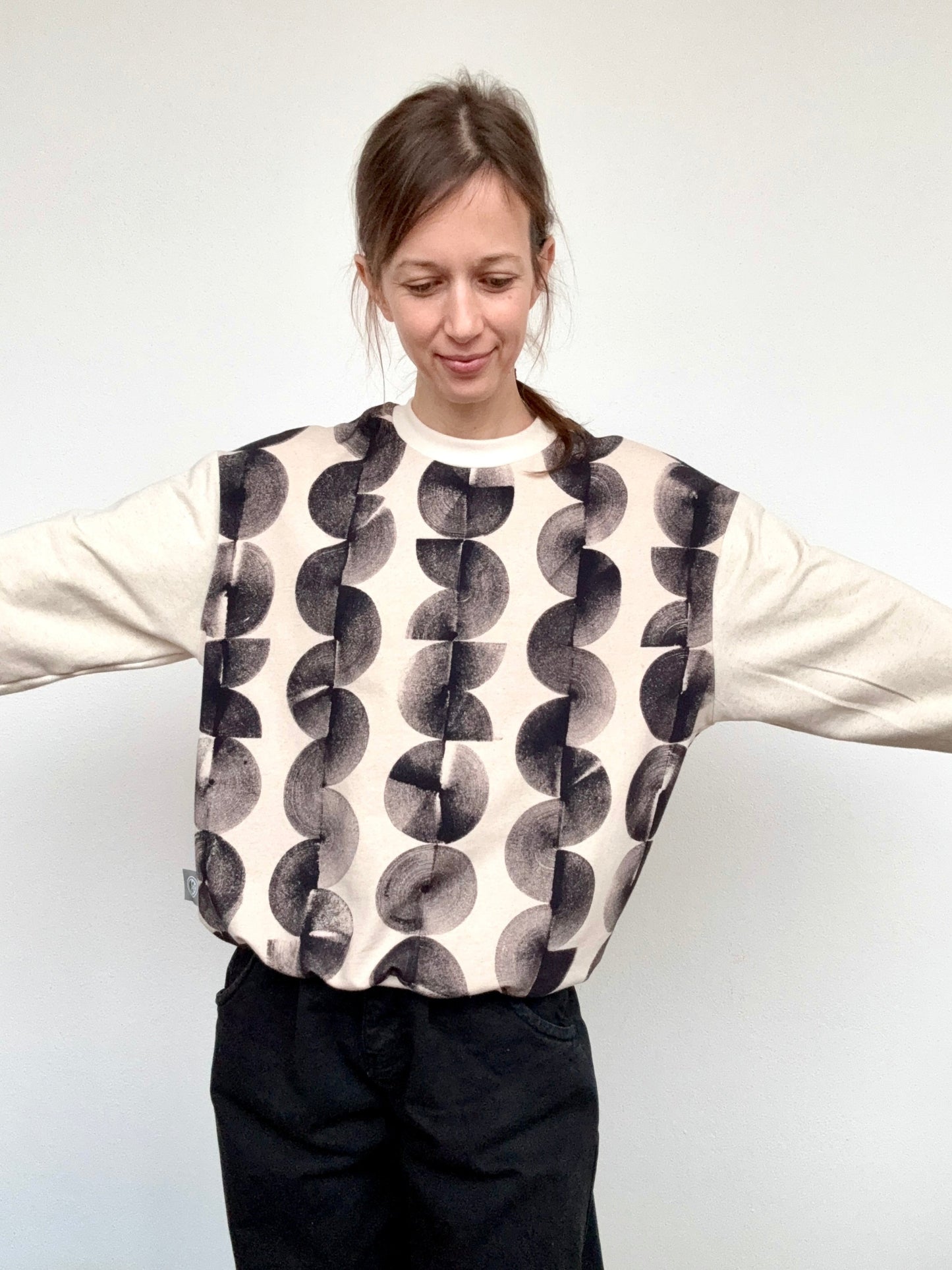 Person wearing a patterned sweater hand-painted with iron paste with a plain background by DOT 'N' POT