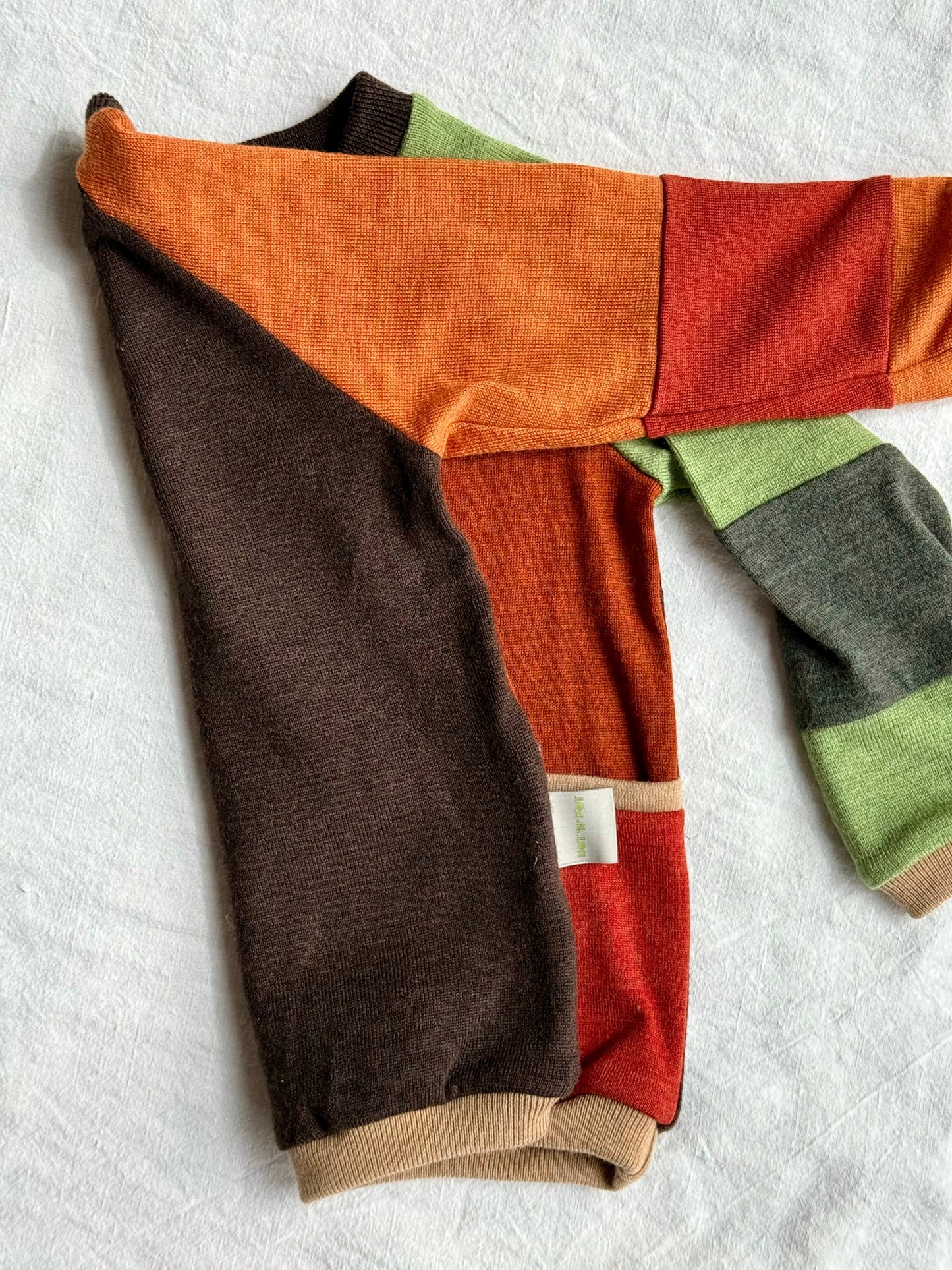 colorful front and dark brown back of an upcycled merino wool sweater on white background