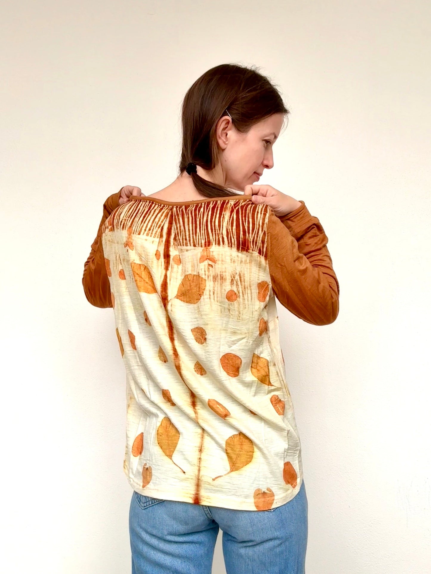 Woman wearing a tie-dye shirt with a pattern of orange eucalyptus leaves