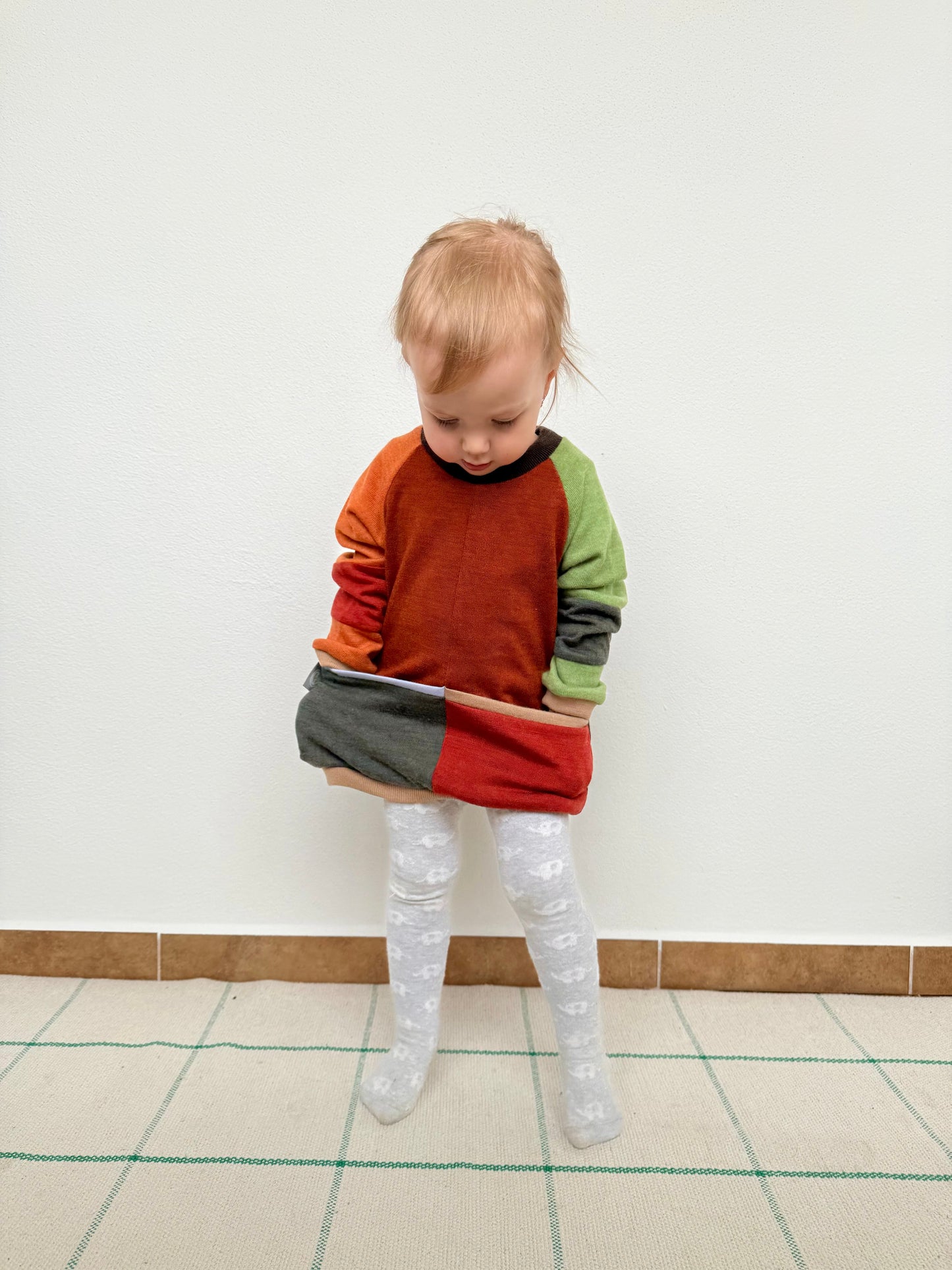 Child wearing a colorful upcycled sweater made of merino wool by DOT 'N' POT