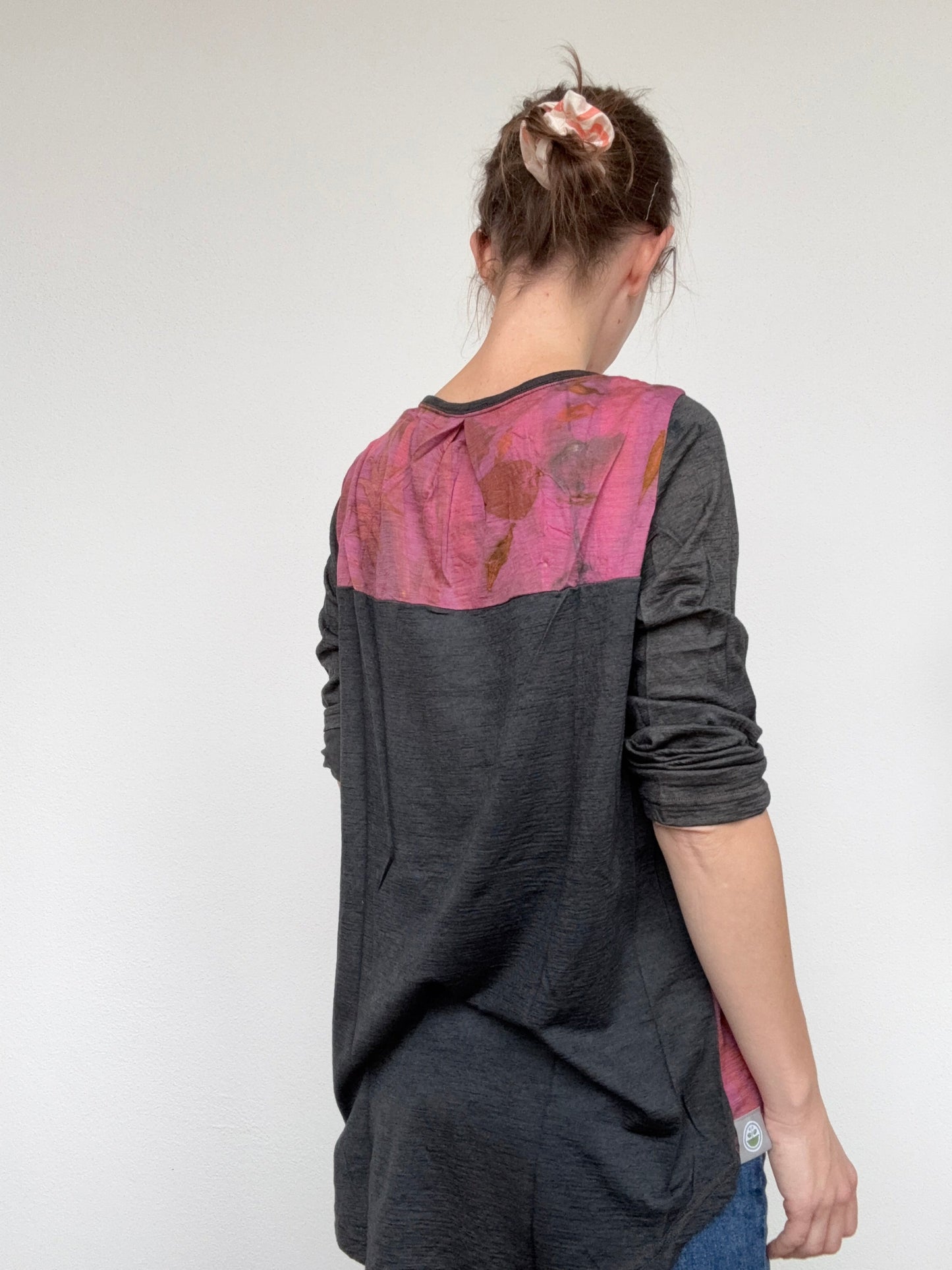 Woman wearing a dark gray naturally dyed t-shirt with pink cochineal dyed accents on a white background