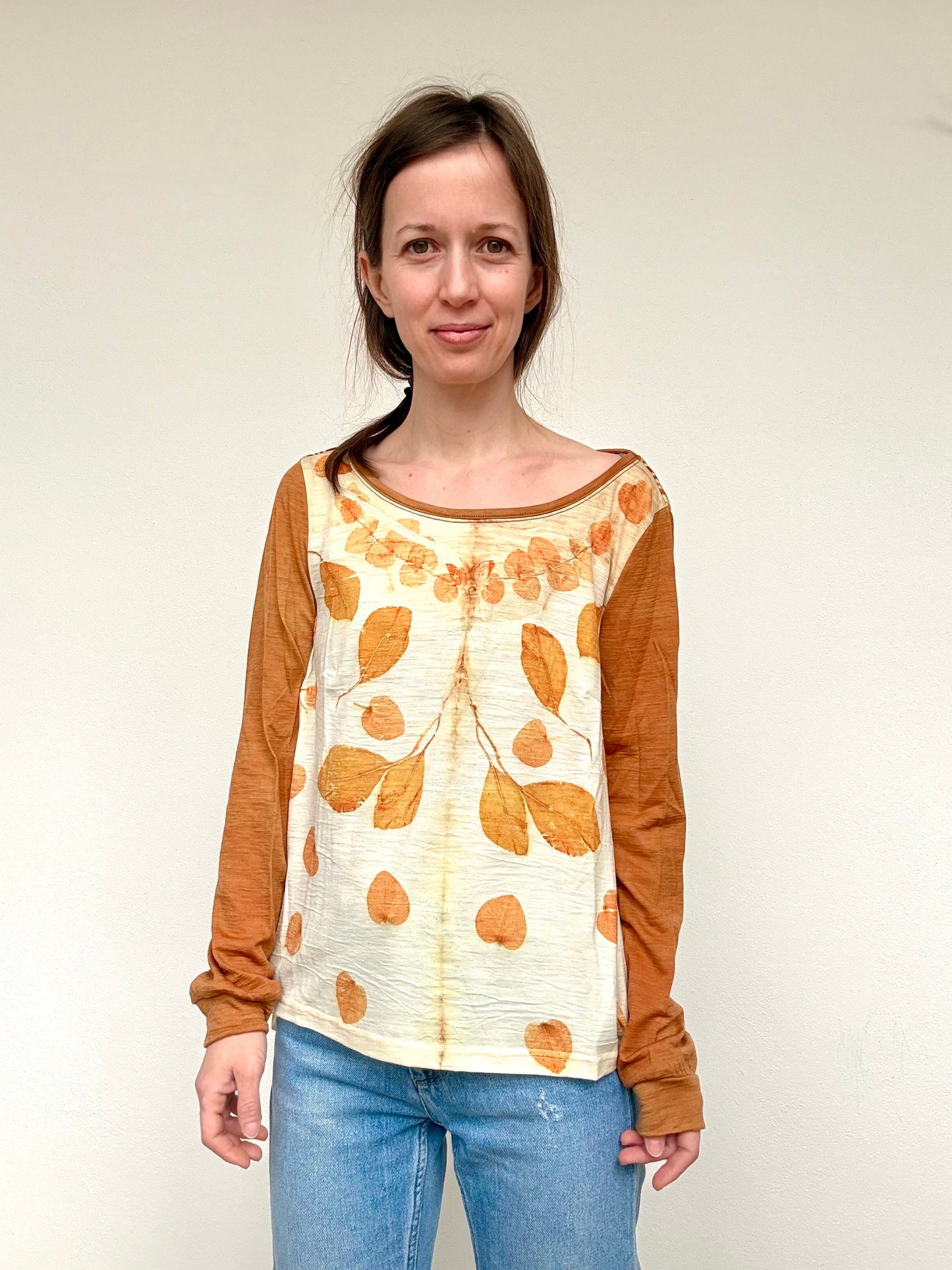 Woman wearing an orange dyed long-sleeve top with an eucalyptus leaf pattern against a plain background by DOT 'N' POT
