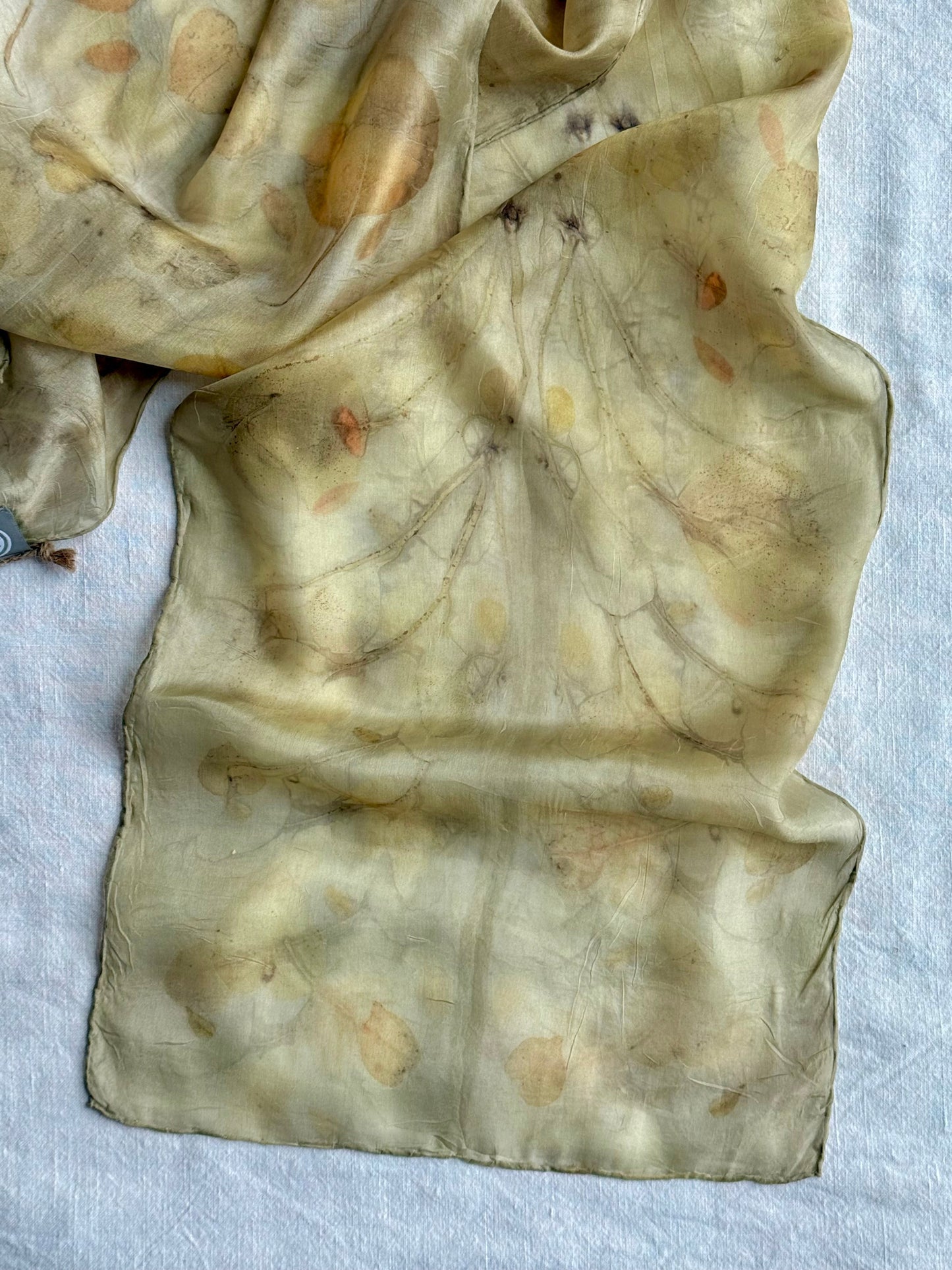 detail of a natural silk scarf dyed with goldenrod and eco-printed with  eucalyptus leaves