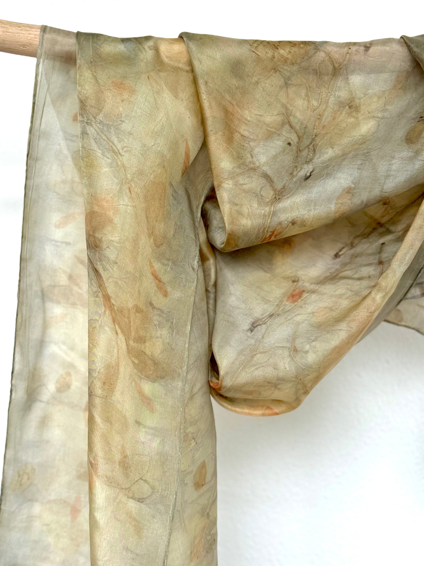 silk scarf naturally dyed with blackberry leaves hanging on a wooden rod by DOT 'N' POT