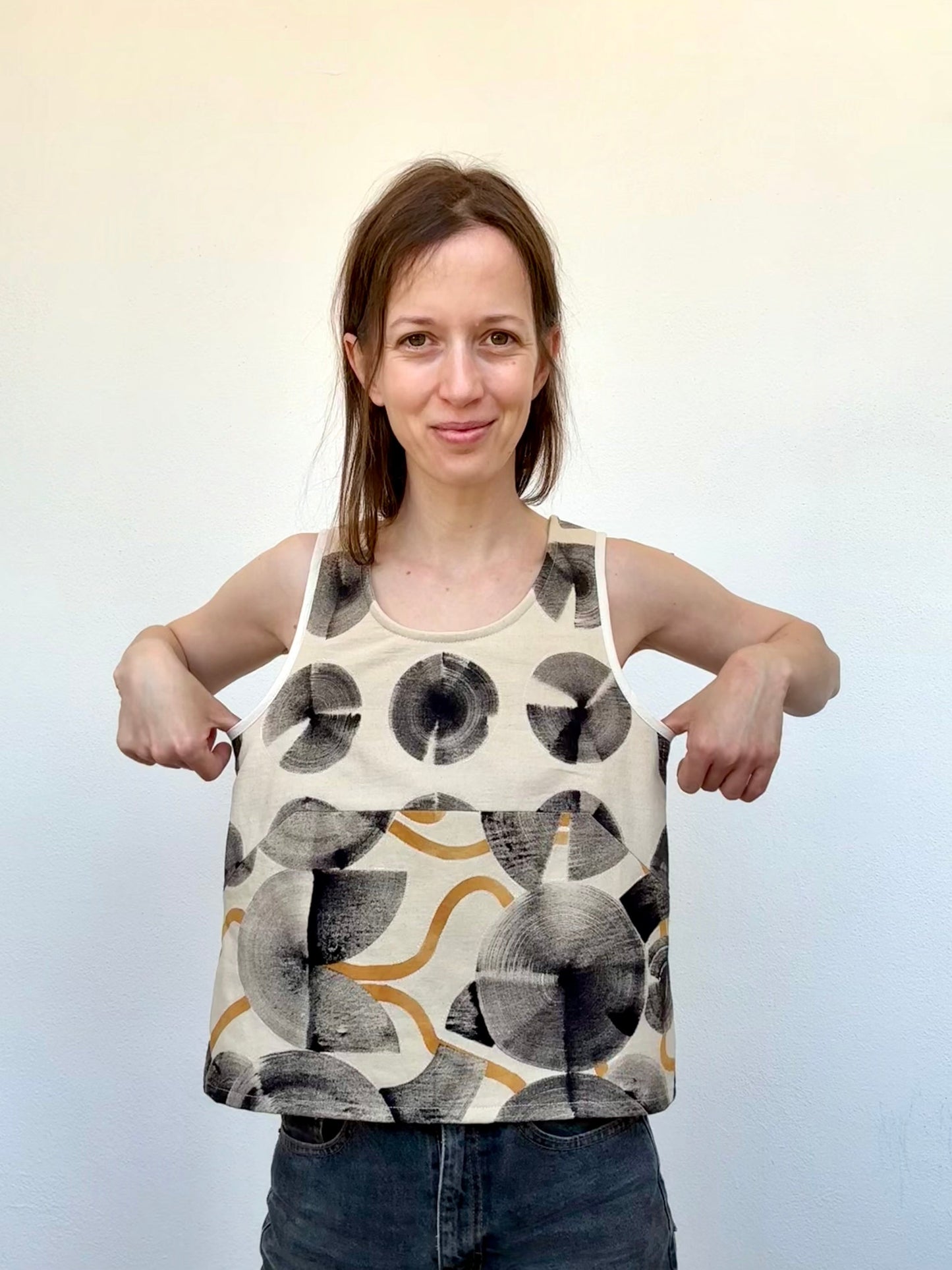 Woman wearing a sleeveless top with abstract pattern on a plain background - naturally dyed and hand-painted with ferrous paste and cosmos dye paste
