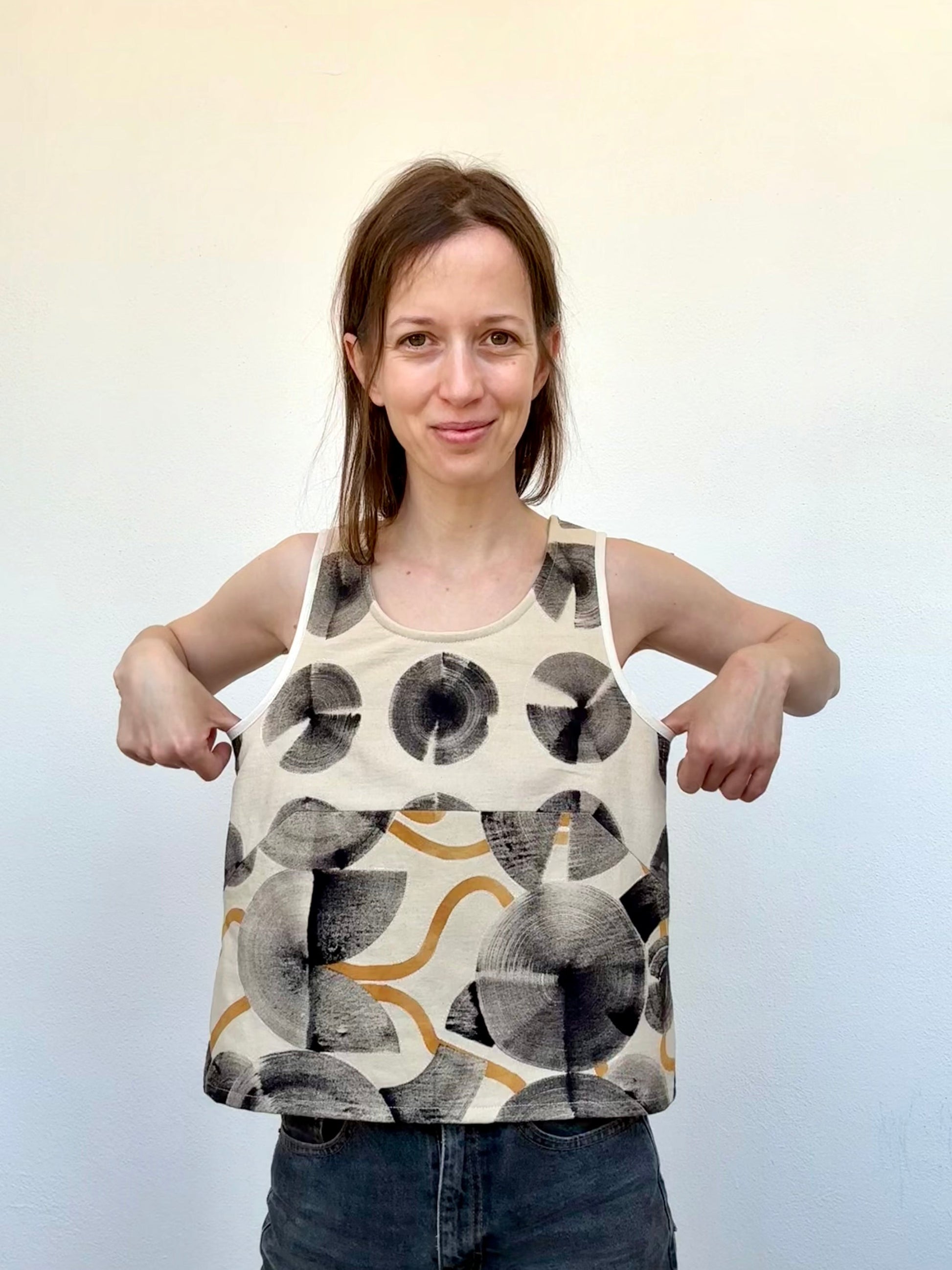 Woman wearing a sleeveless top with abstract pattern on a plain background - naturally dyed and hand-painted with ferrous paste and cosmos dye paste