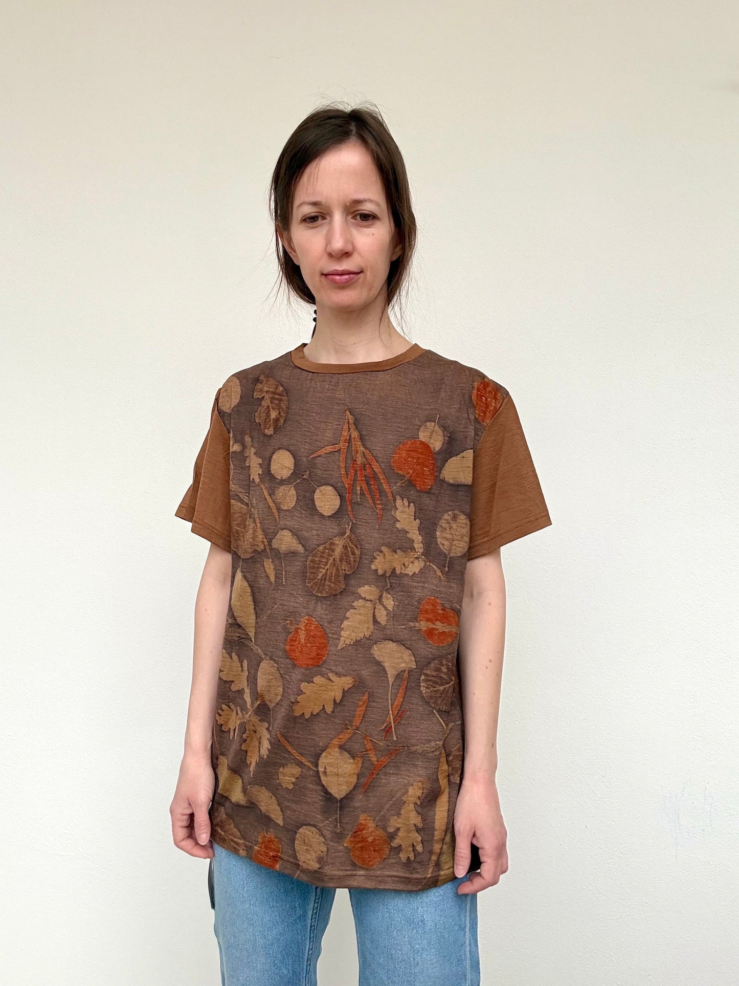women standing in an eco-printed orange, gray and brown colored t-shirt against a white background