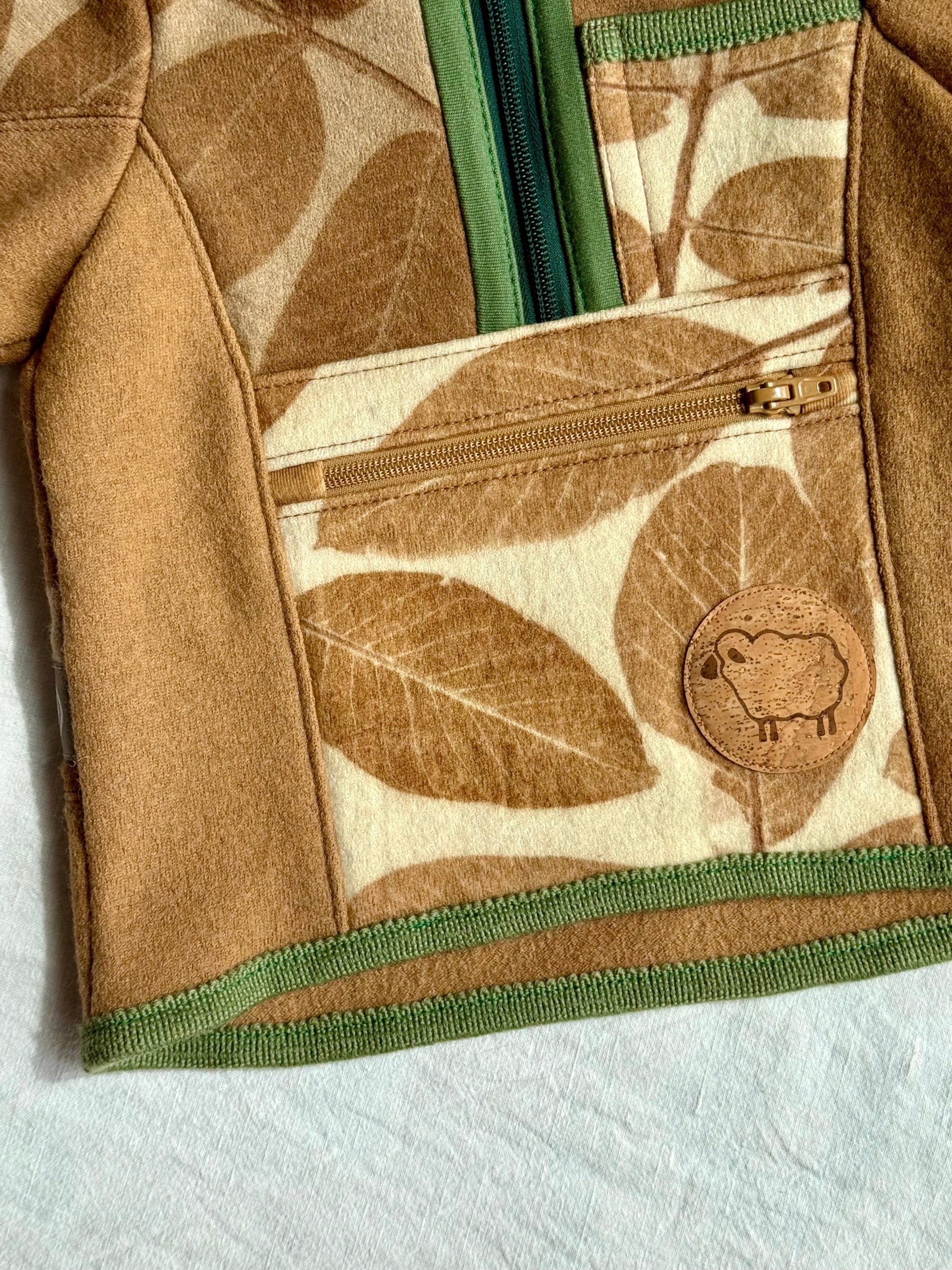 Close-up of a merino wool sweater for kids with zipper pocket and a cork sheep patch