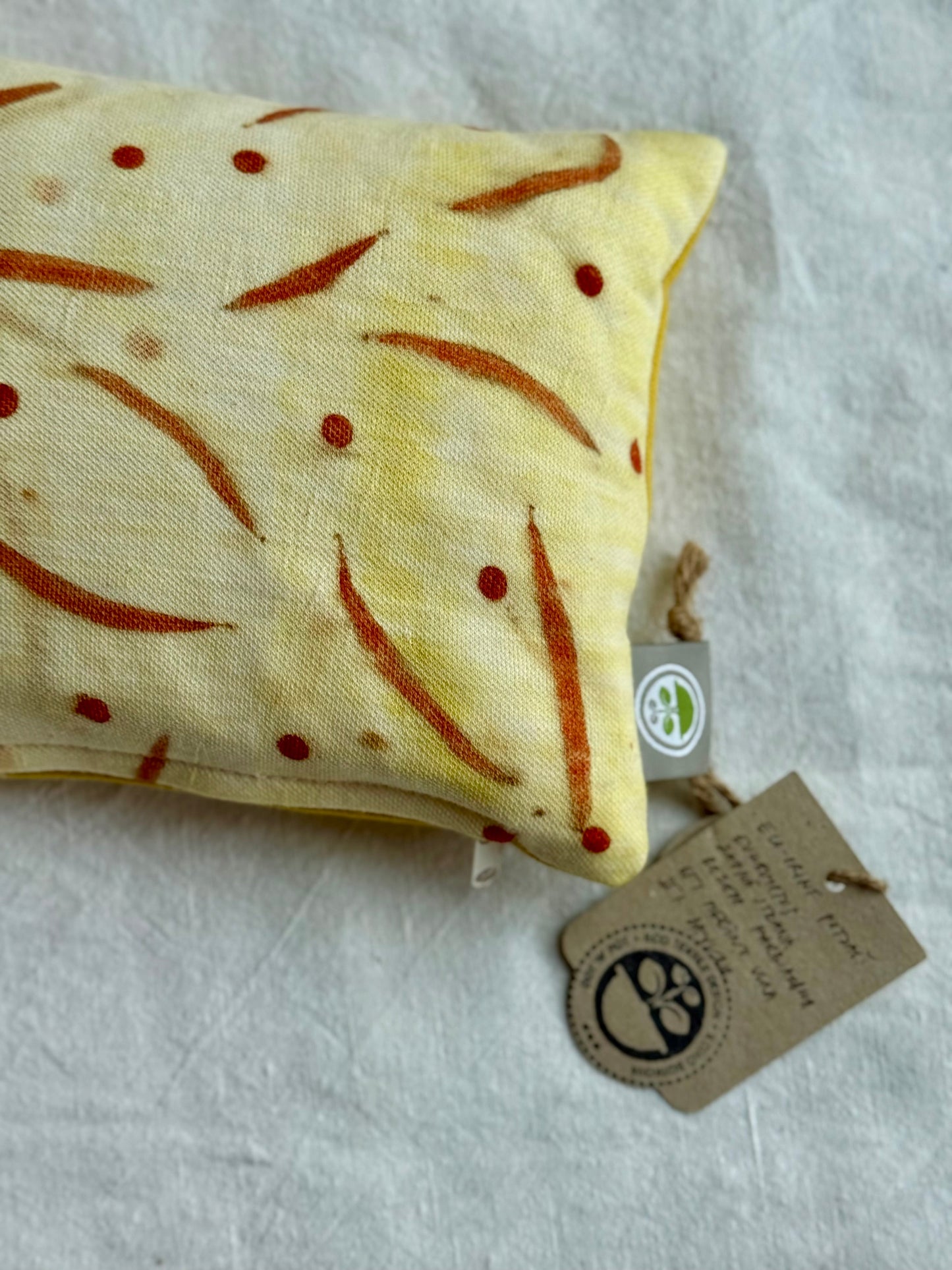 herbal red-yellow pillow close-up with tag naturally dyed and eco-printed