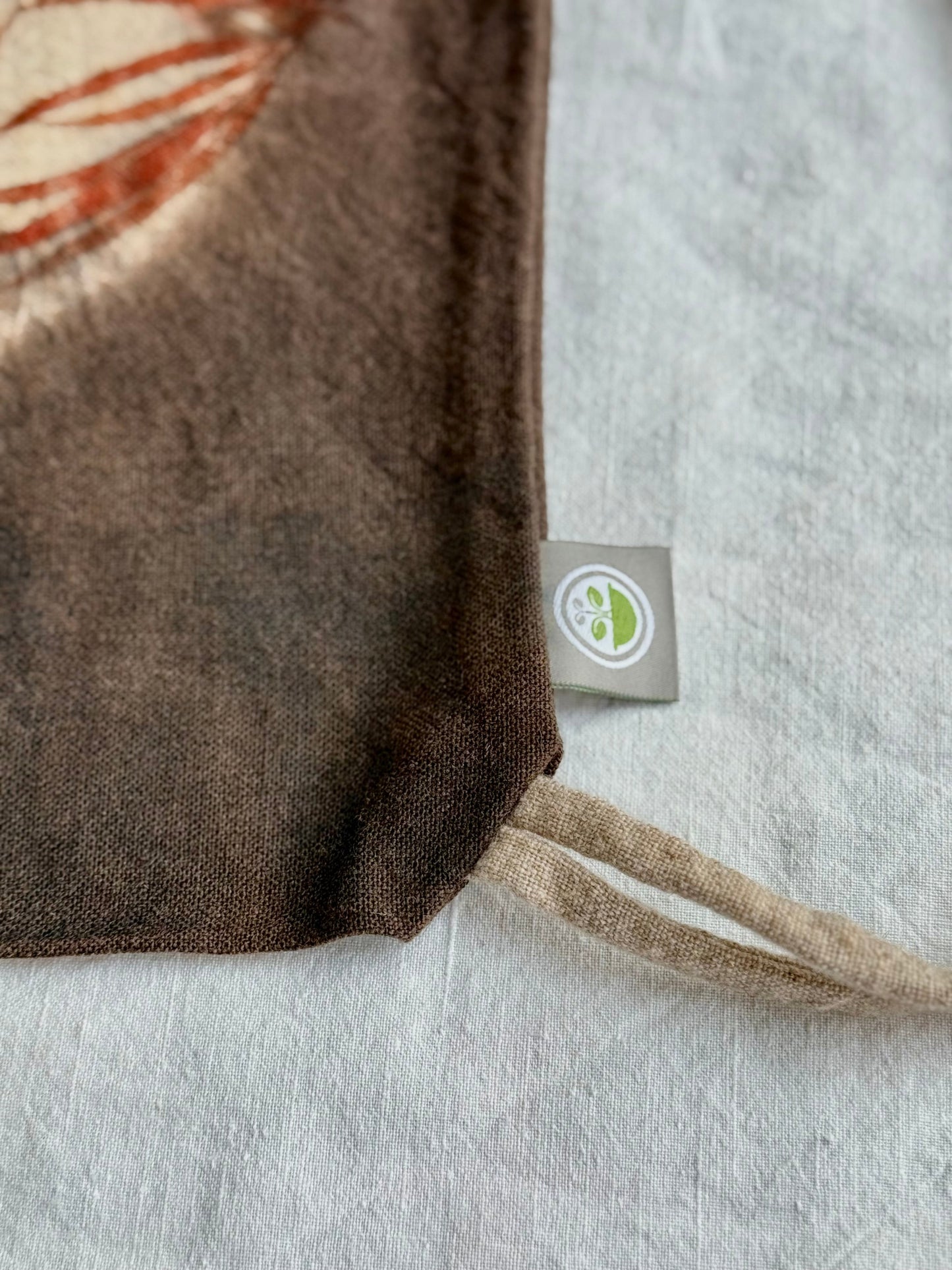 Close-up of a fabric texture with visible brand tag on a neutral background by DOT 'N' POT