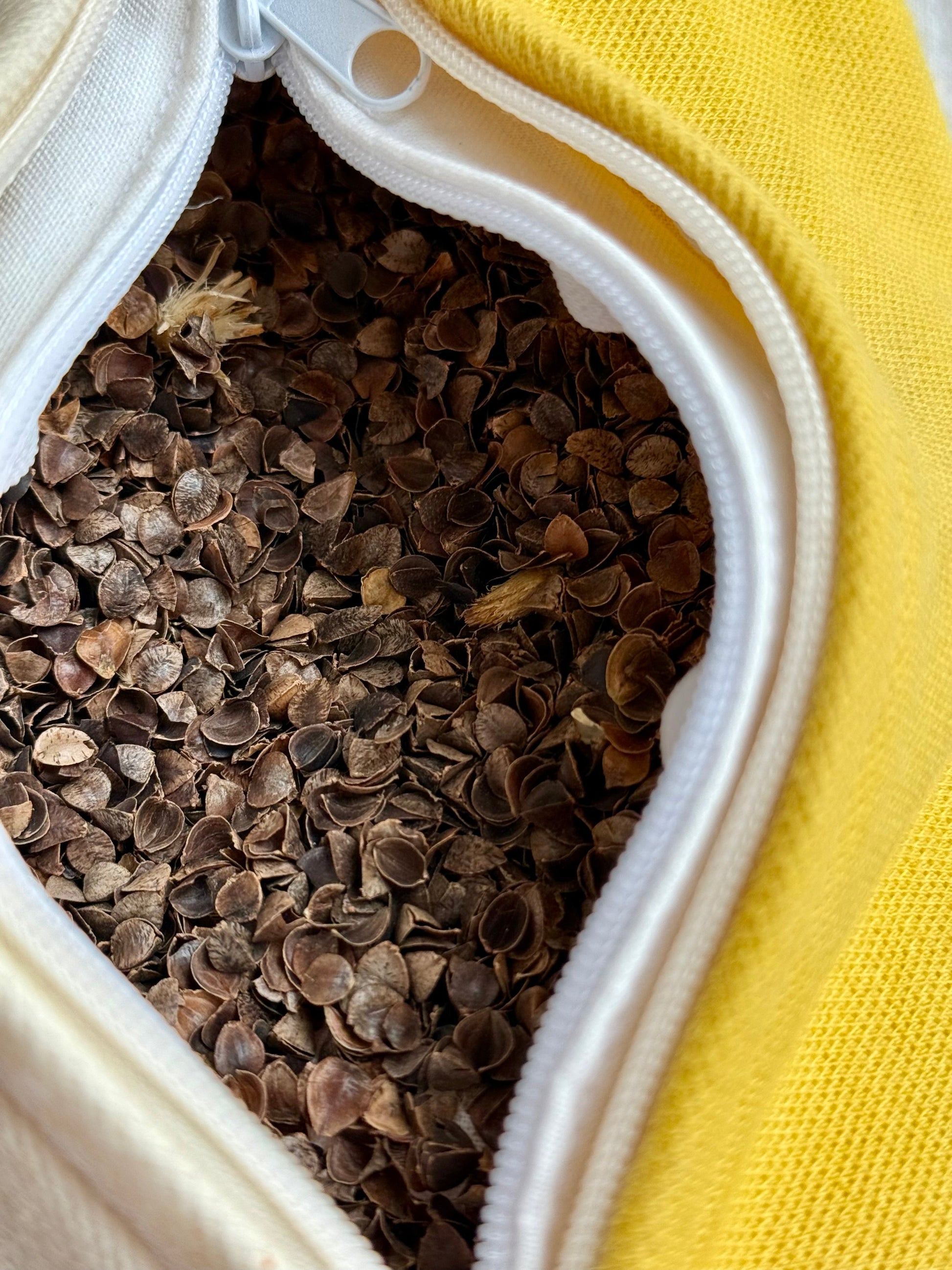 Close-up of a natural weld yellow herbal pillow with a white zipper, filled with buckwheat hulls 