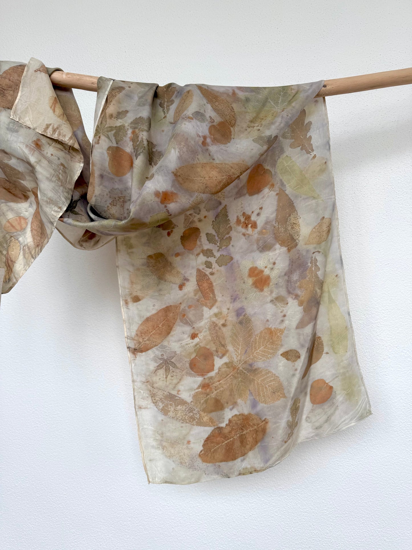 naturally dyed light purple silk scarf with eco-print hanging on a wooden rod by DOT 'N' POT