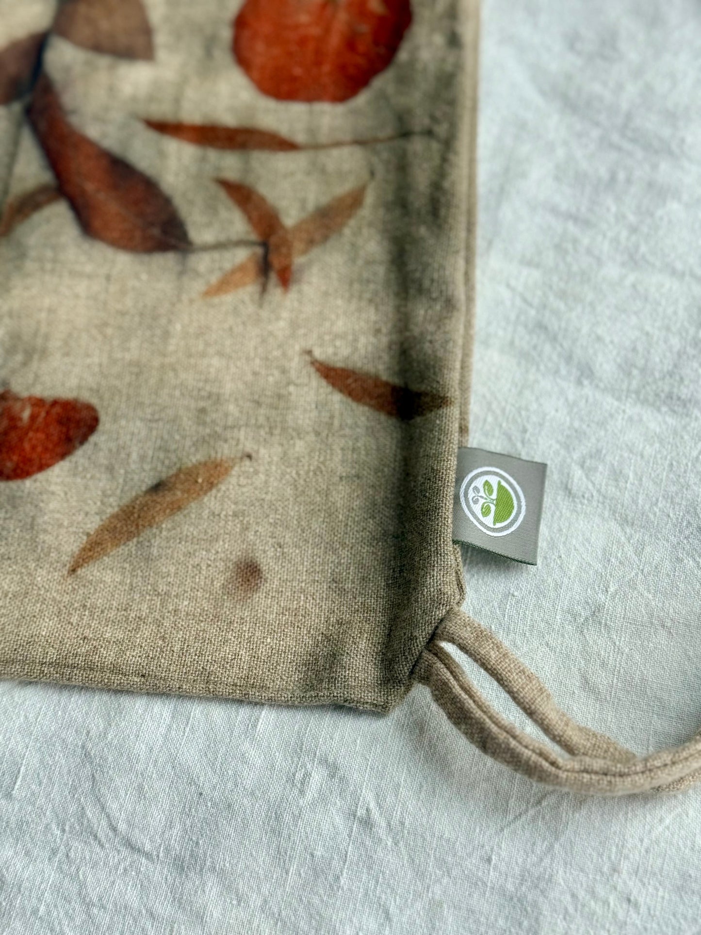 Fabric close-up with leaf pattern and a visible brand tag on a light background by DOT 'N' POT