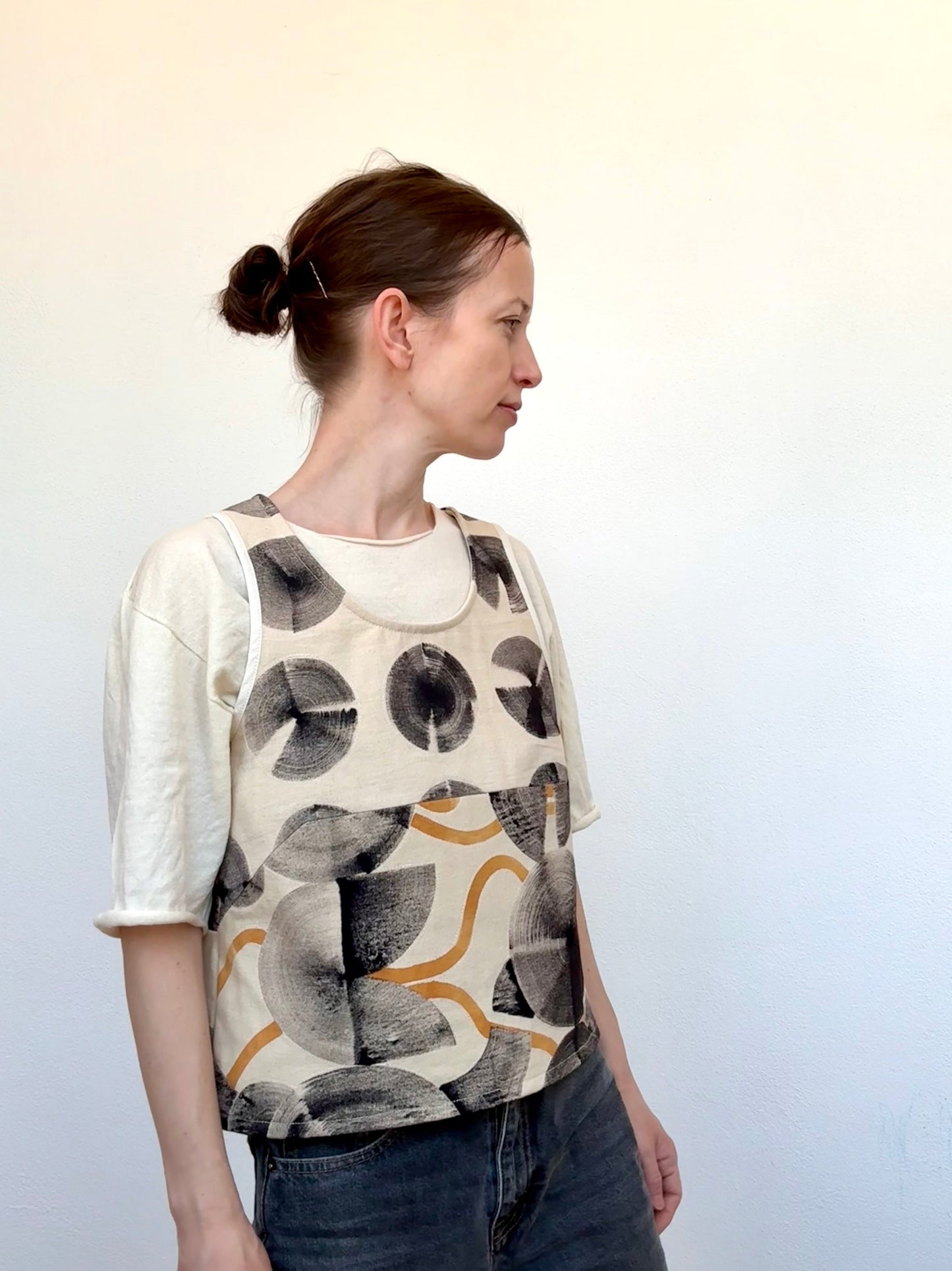 Woman wearing a hand-painted naturally dyed vest with abstract designs against a plain background by DOT 'N' POT