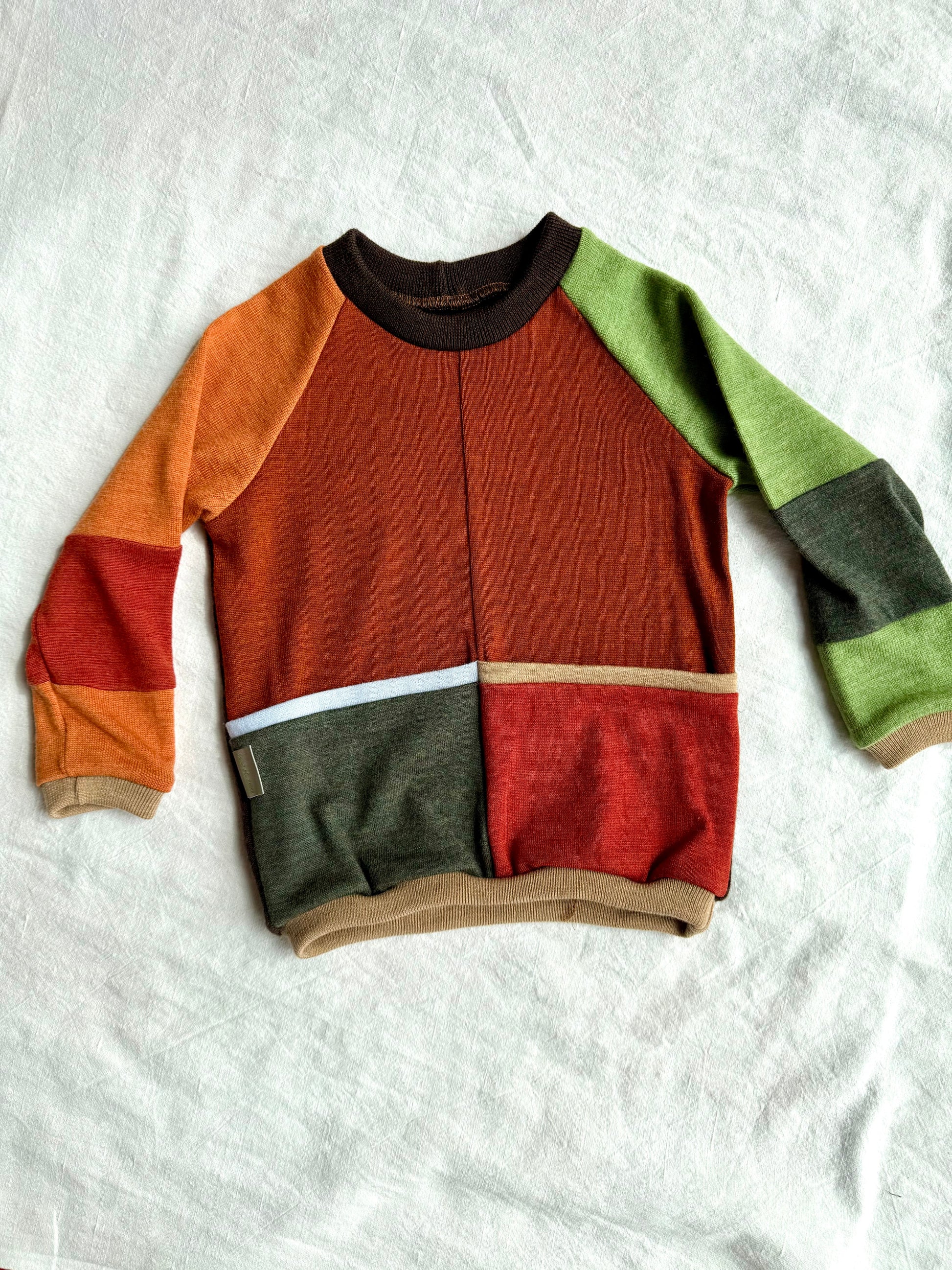 Upcycled merino wool sweater for kids with brown, green, and orange sections on by DOT 'N' POT