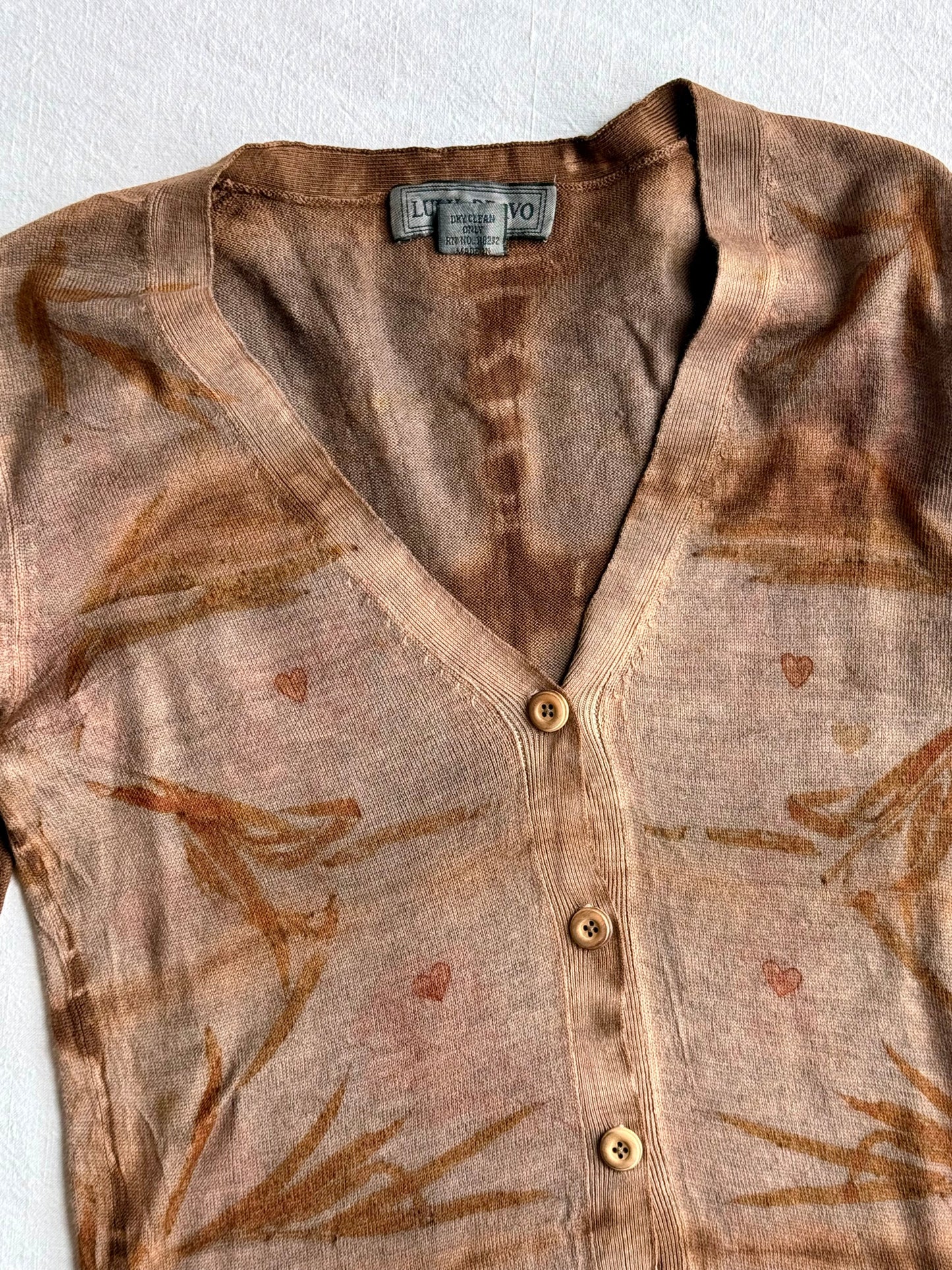 front of an upcycled woolen sweater, naturally dyed with walnut and cutch, eco-printed with heart shaped patterns