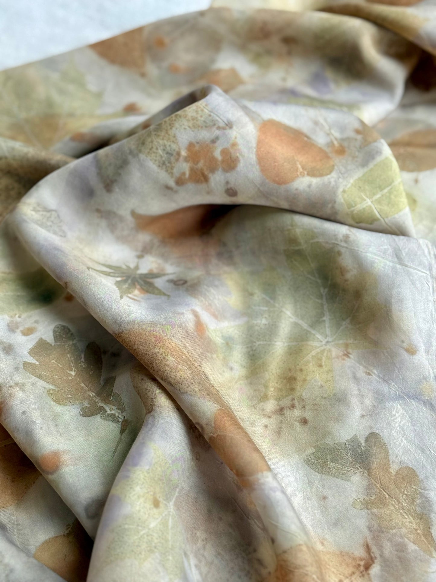 Close-up of a folded silk scarf with a floral pattern on a light background 