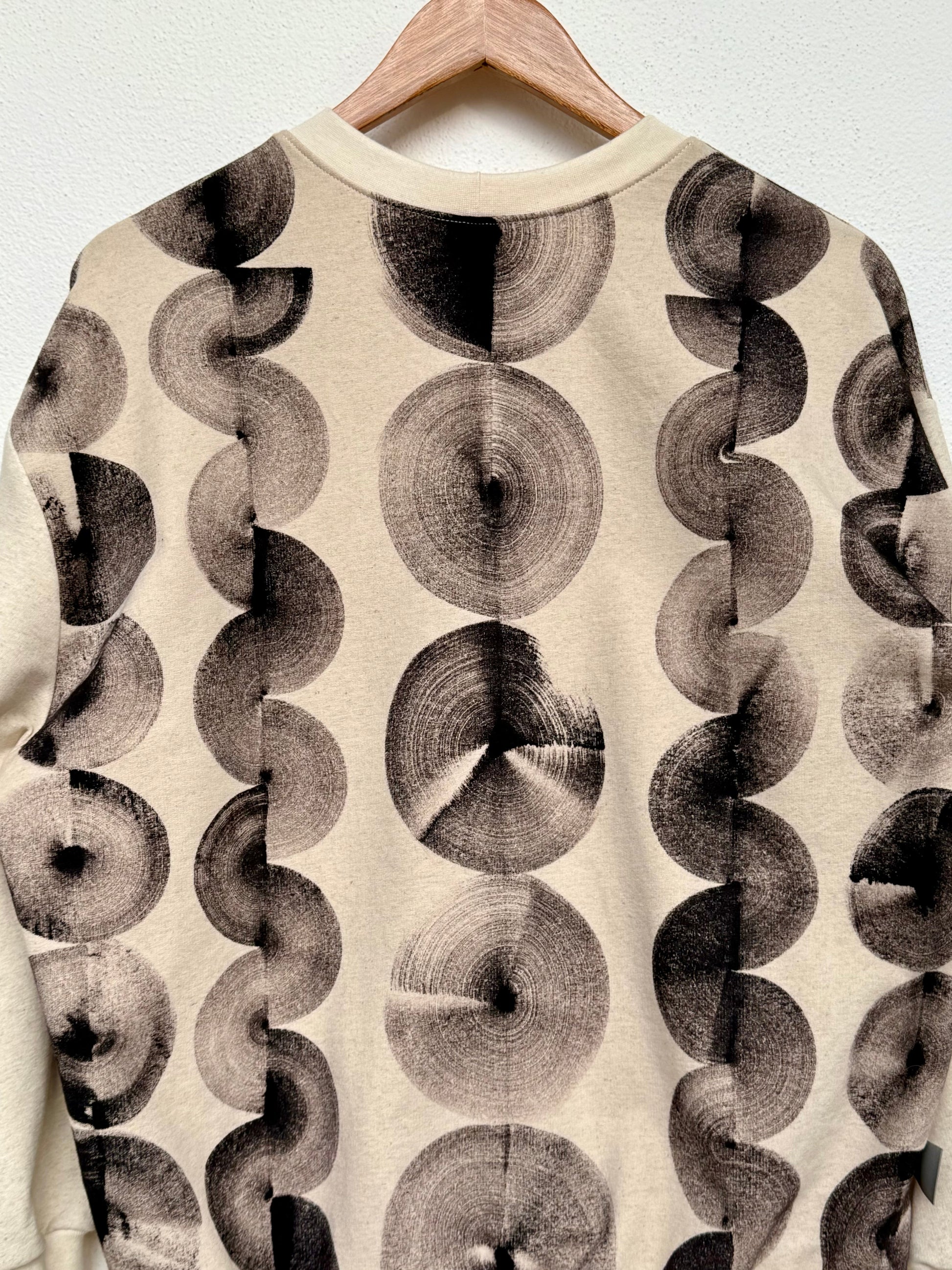 Sweatshirt with black circular hand-painted pattern made with iron paste on a natural colored background