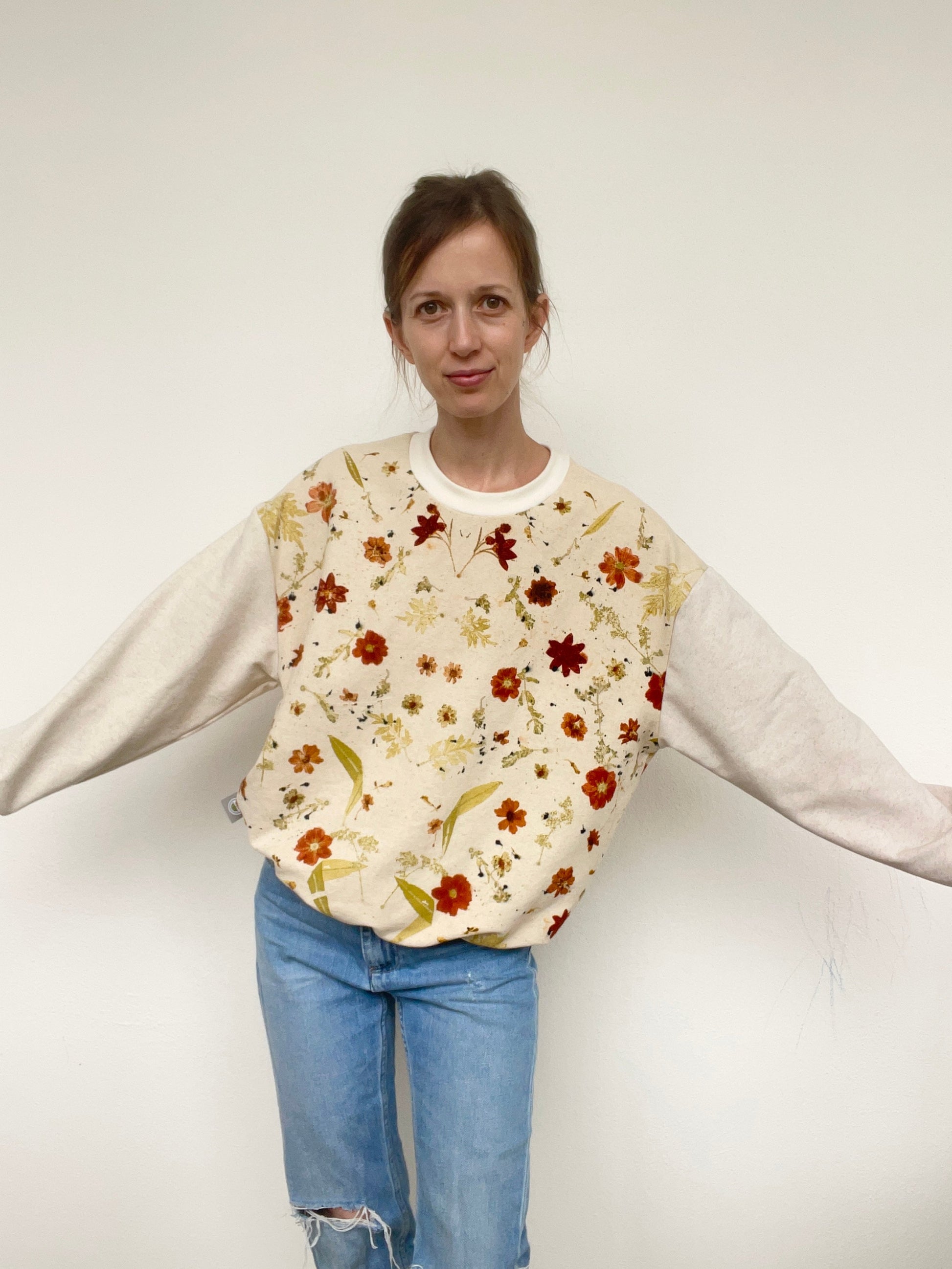 woman wearing an eco-printed, floral patterned sweater with jeans