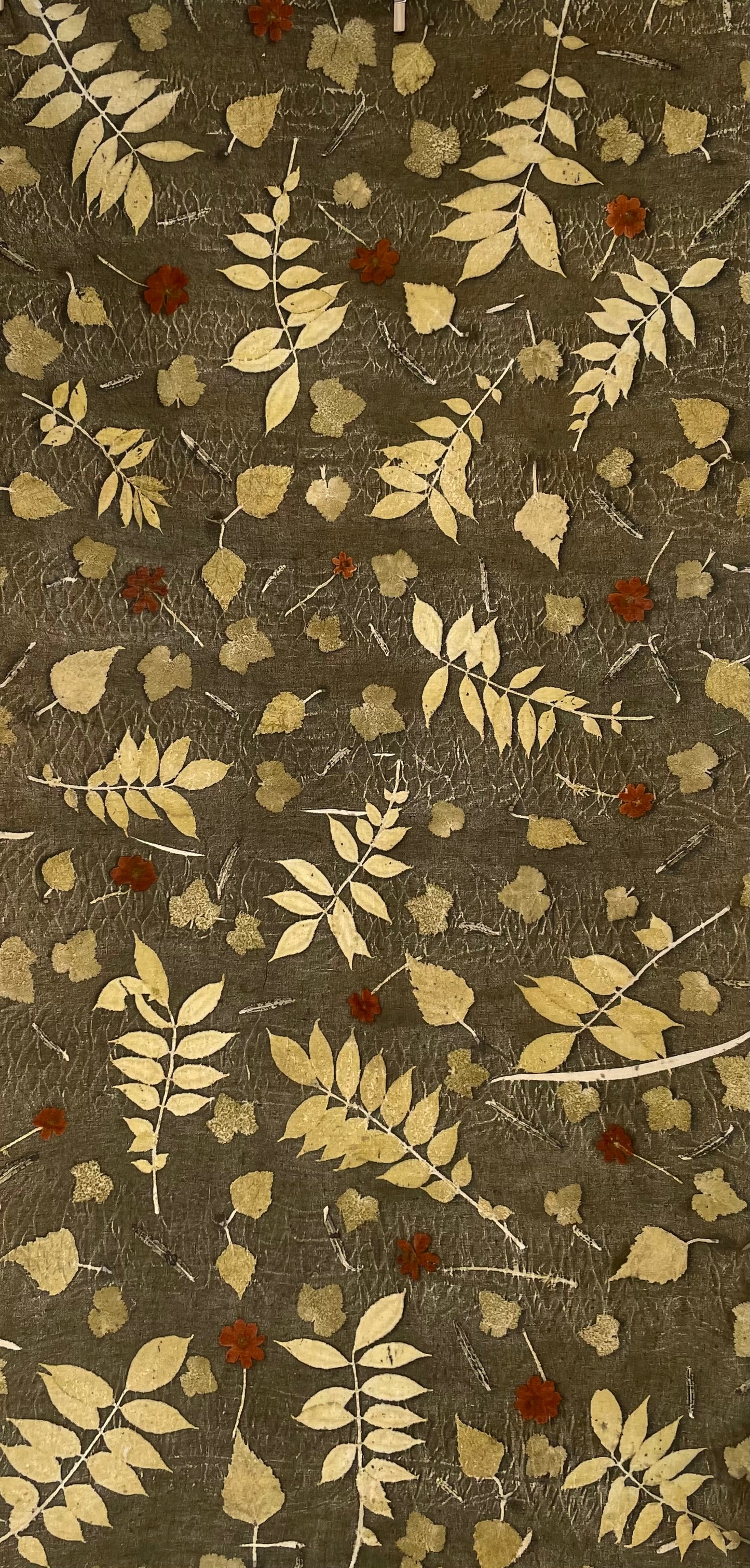 Textile with leaf pattern eco-printed  on linen fabric with a green background 