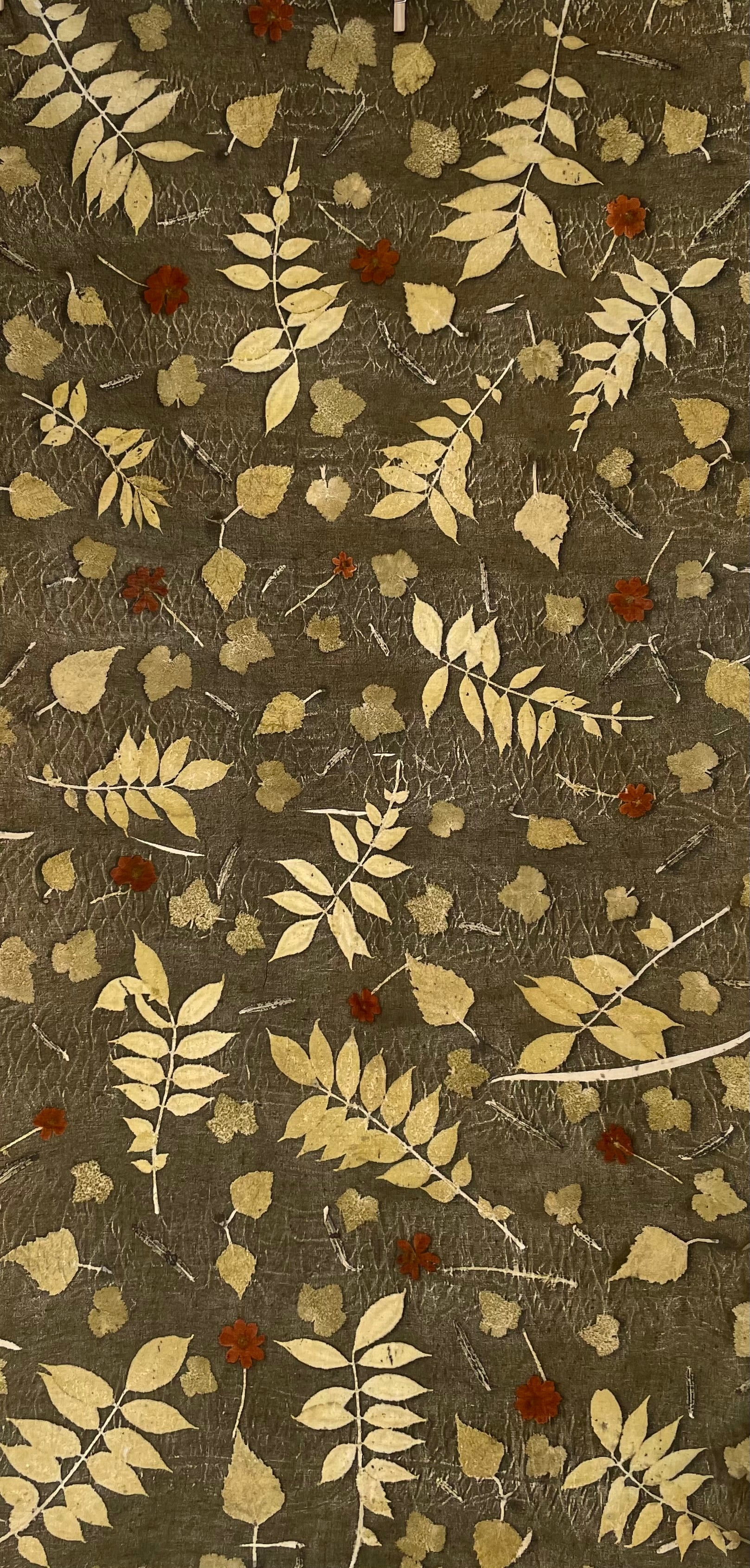 Textile with leaf pattern eco-printed  on linen fabric with a green background 