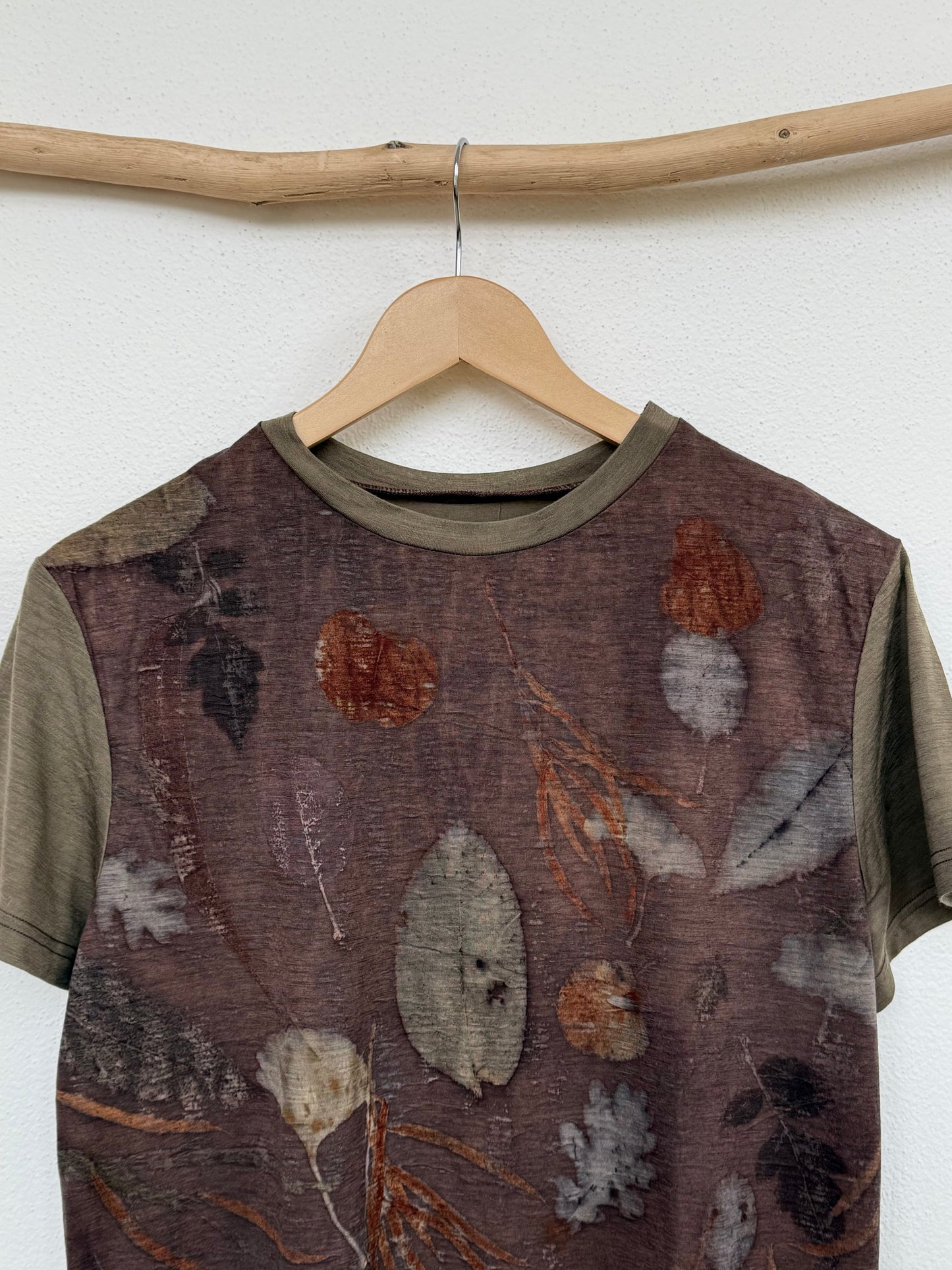 merino wool t-shirt with nature-themed design on a wooden hanger against a white wall