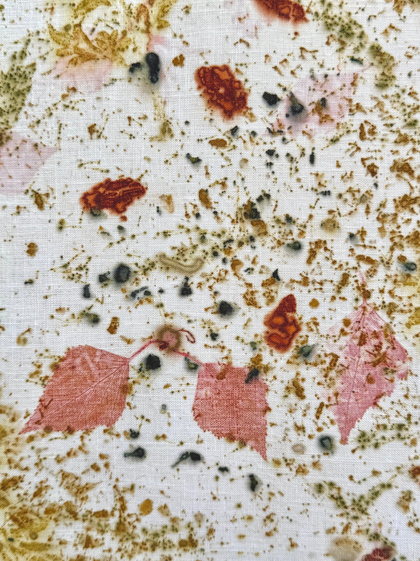 Close-up of an eco-printed hemp fabric with madder red infused birch leaves and  lady's bedstraw flowers