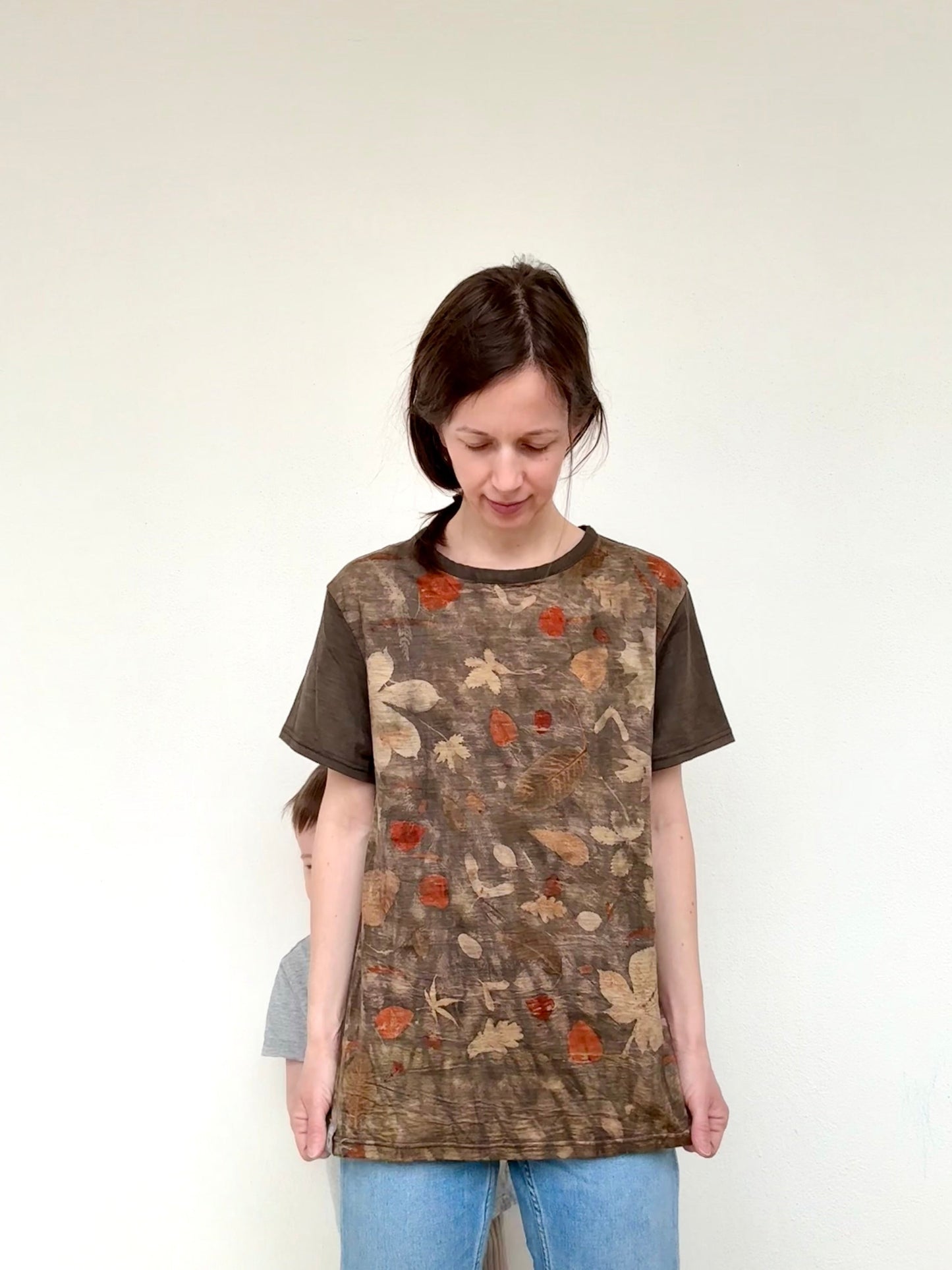 Woman wearing a brown-gray t-shirt with eco-printed plant pattern against a white background